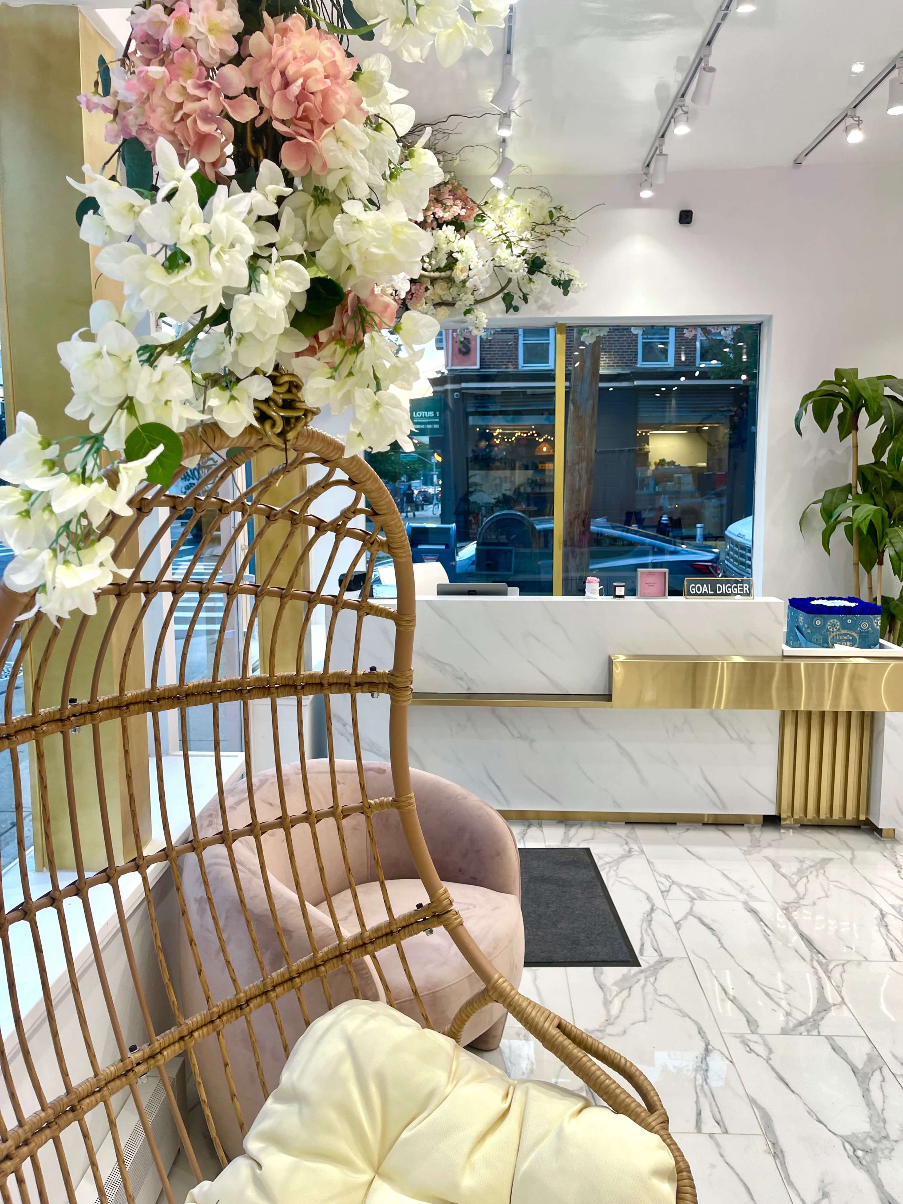 A rattan chair adorned with flowers sits in a well-lit reception area featuring marble floors and a sleek service counter.
