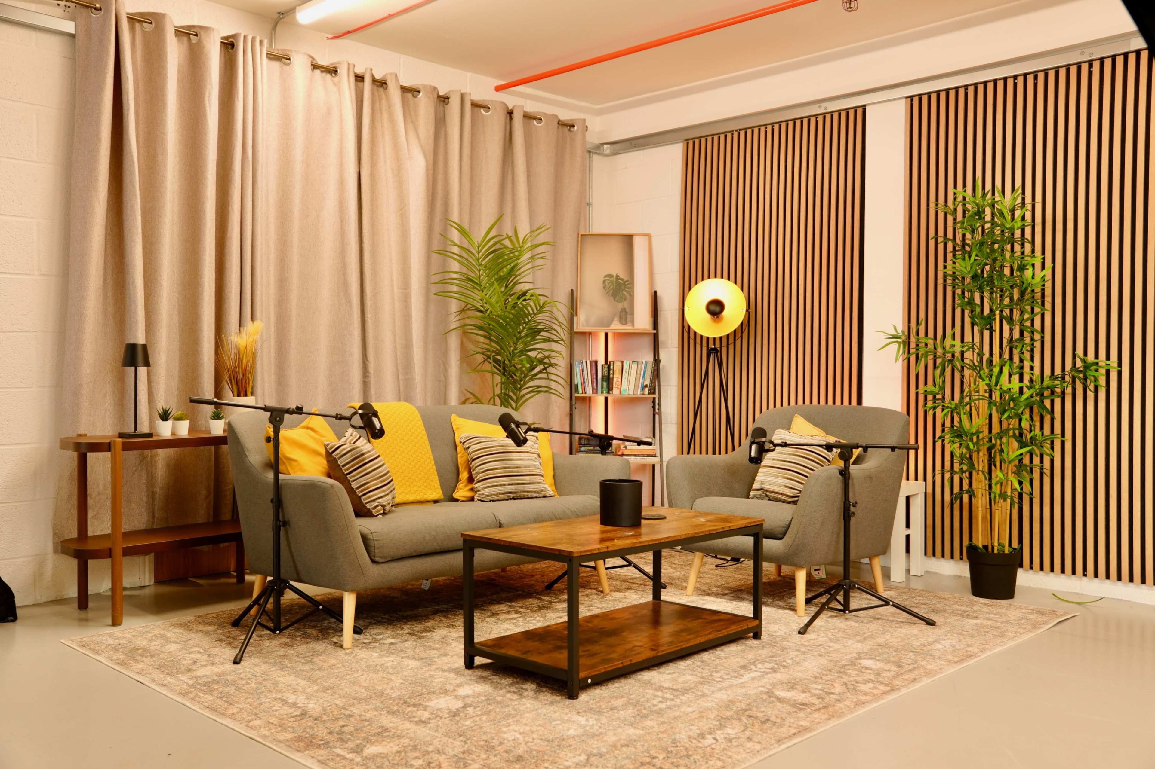 The image shows a modern living room setup featuring a gray sofa with yellow accents, a wooden coffee table, and plants, with soft lighting and textured curtains.