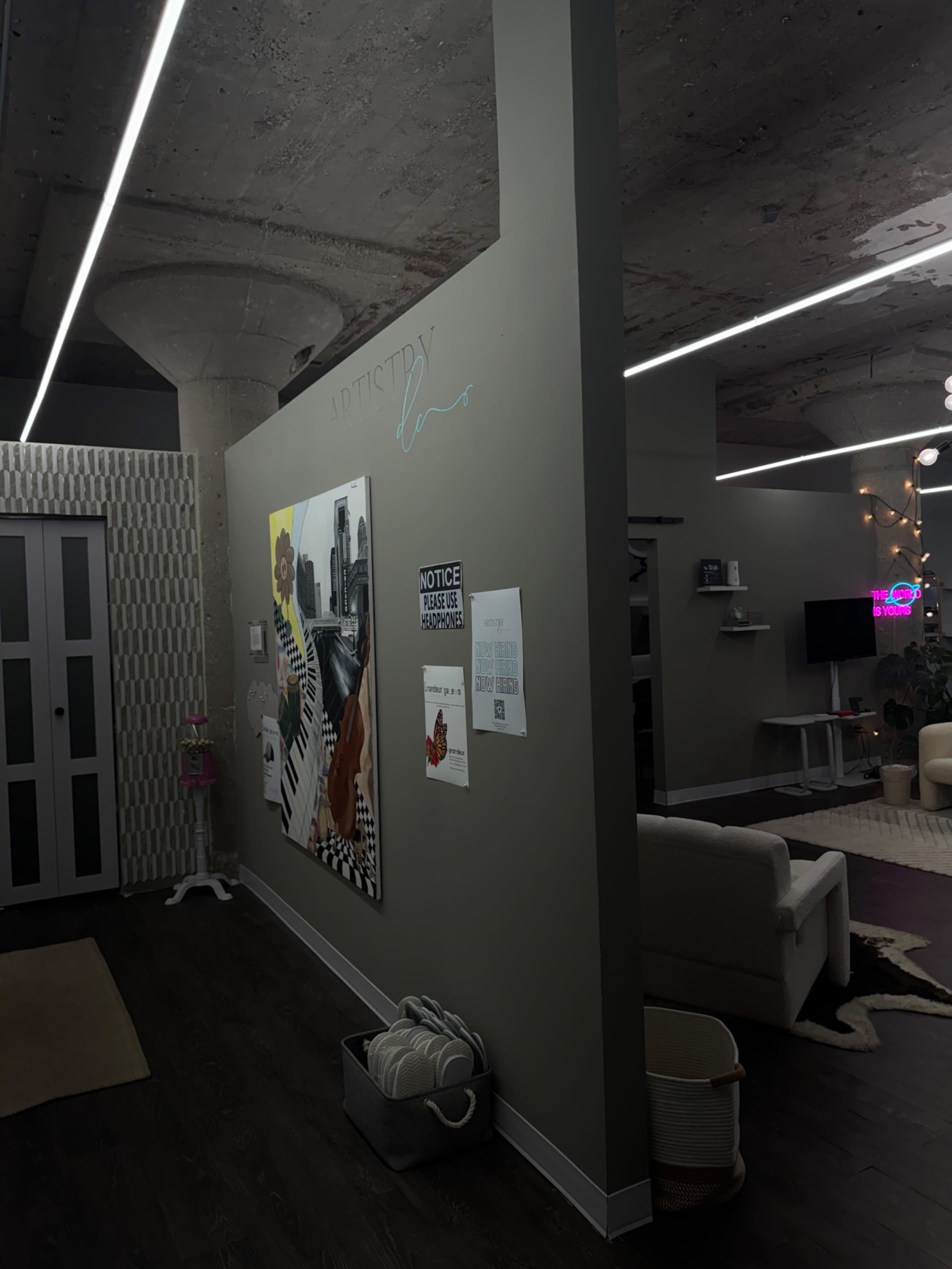 The image shows a modern interior space featuring a wall with artwork, a couch, and various decor elements under dim lighting.