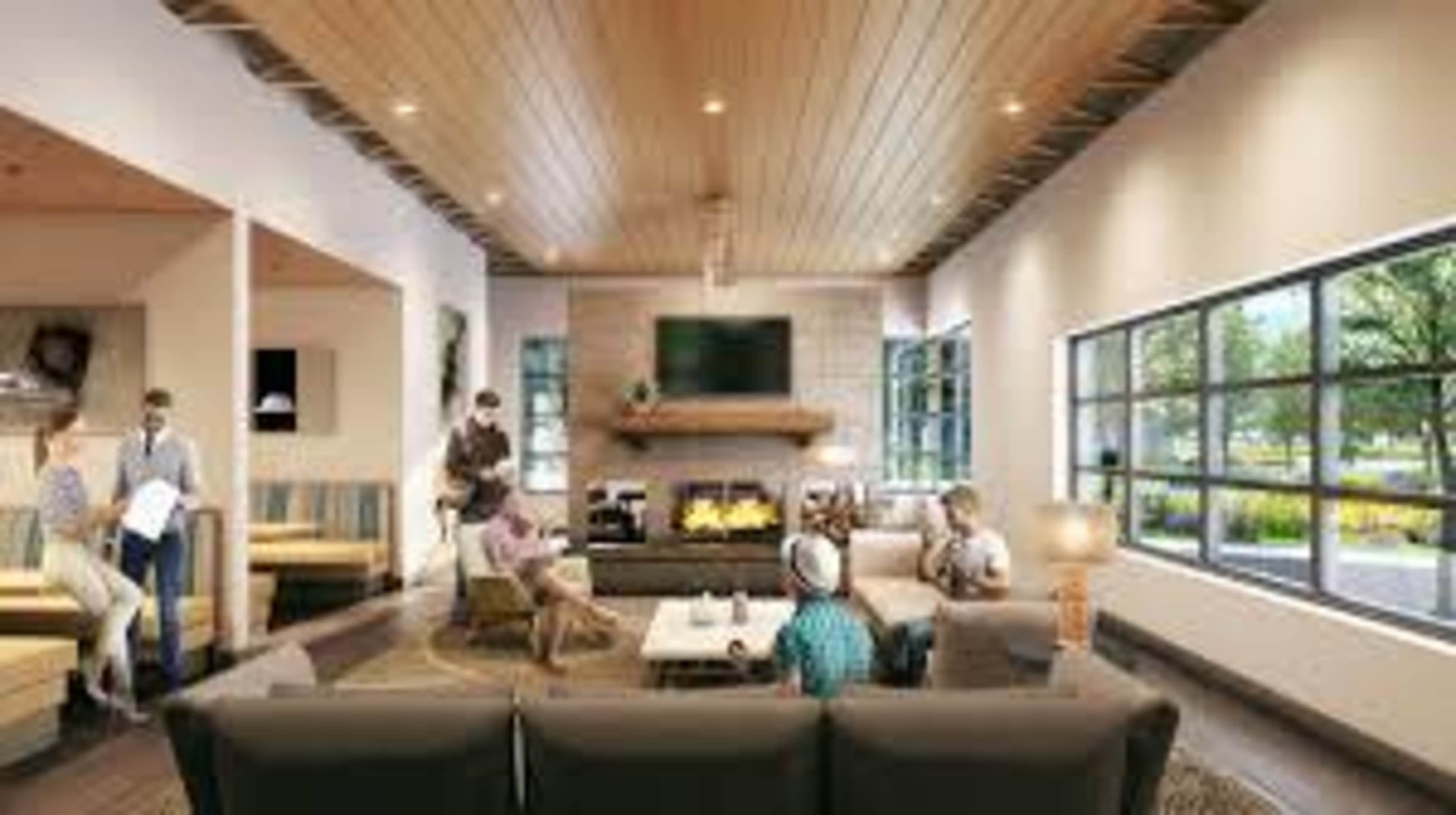 A spacious living room features a modern design with comfortable seating, a central fireplace, and large windows letting in natural light.