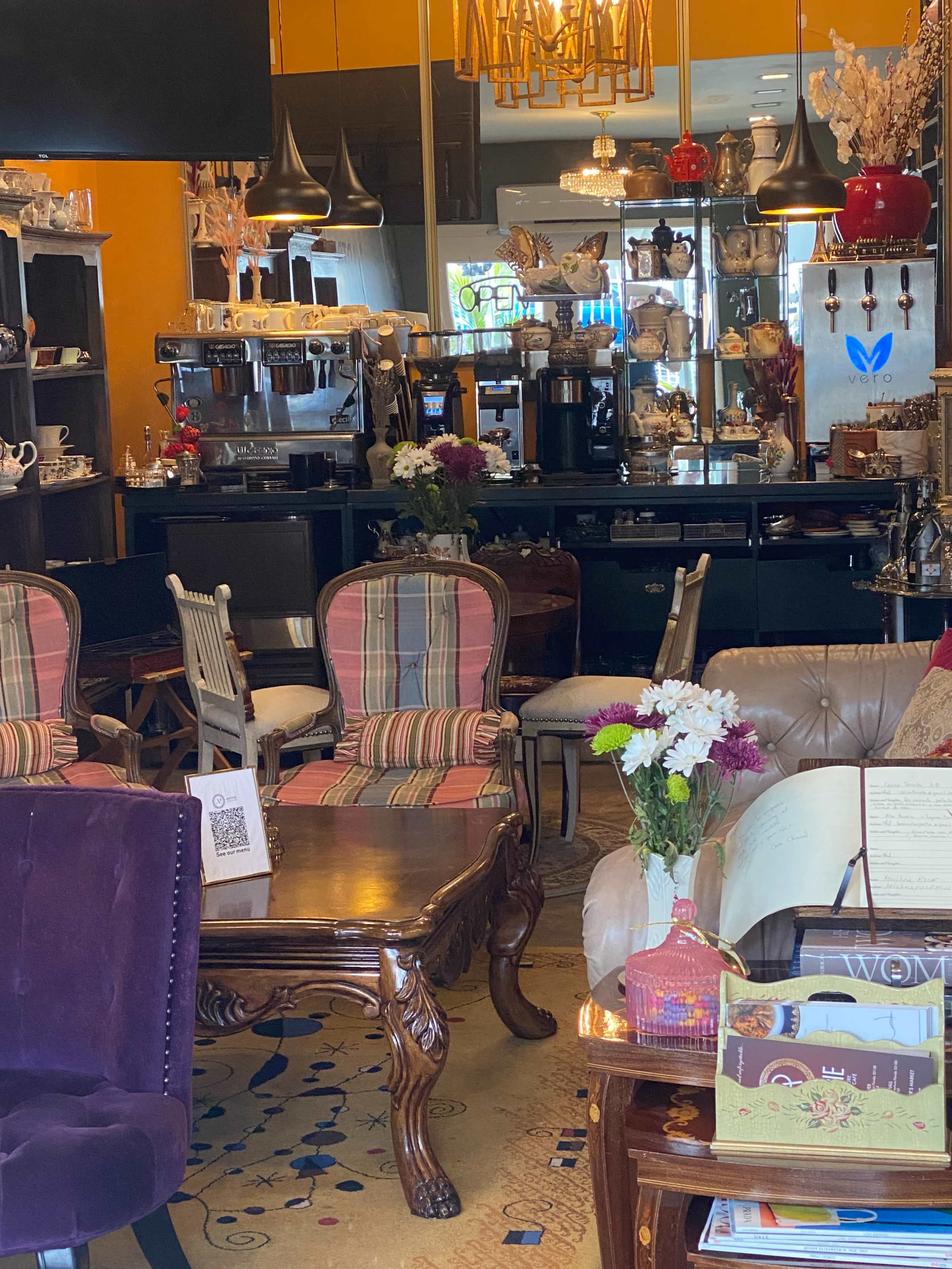 A cozy café interior with various seating options, a wooden table, and decorative items on display.