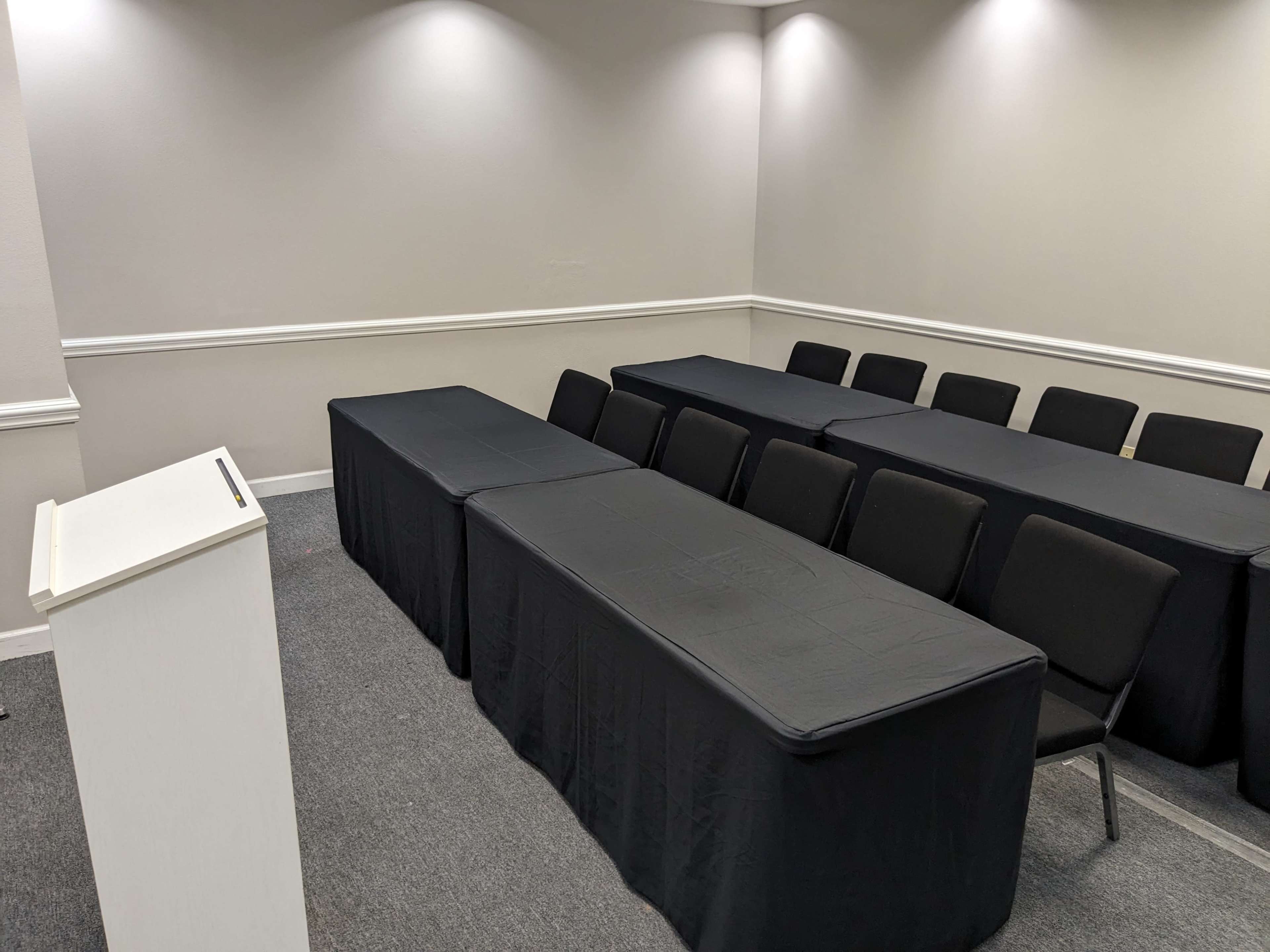A conference room is set up with several rows of chairs facing a podium and tables covered in black cloth.