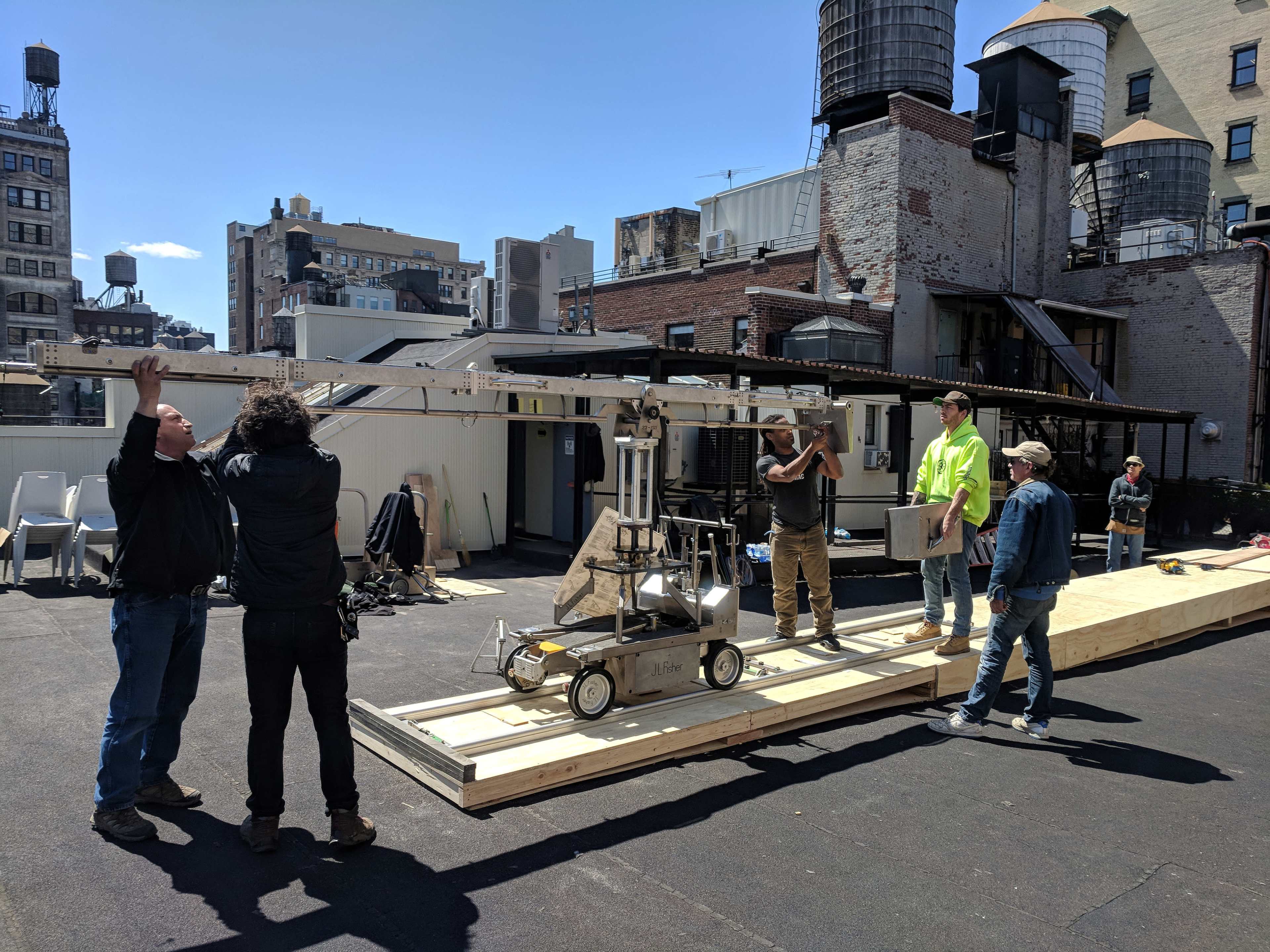 A group of people is assembling equipment on a rooftop in an urban setting.