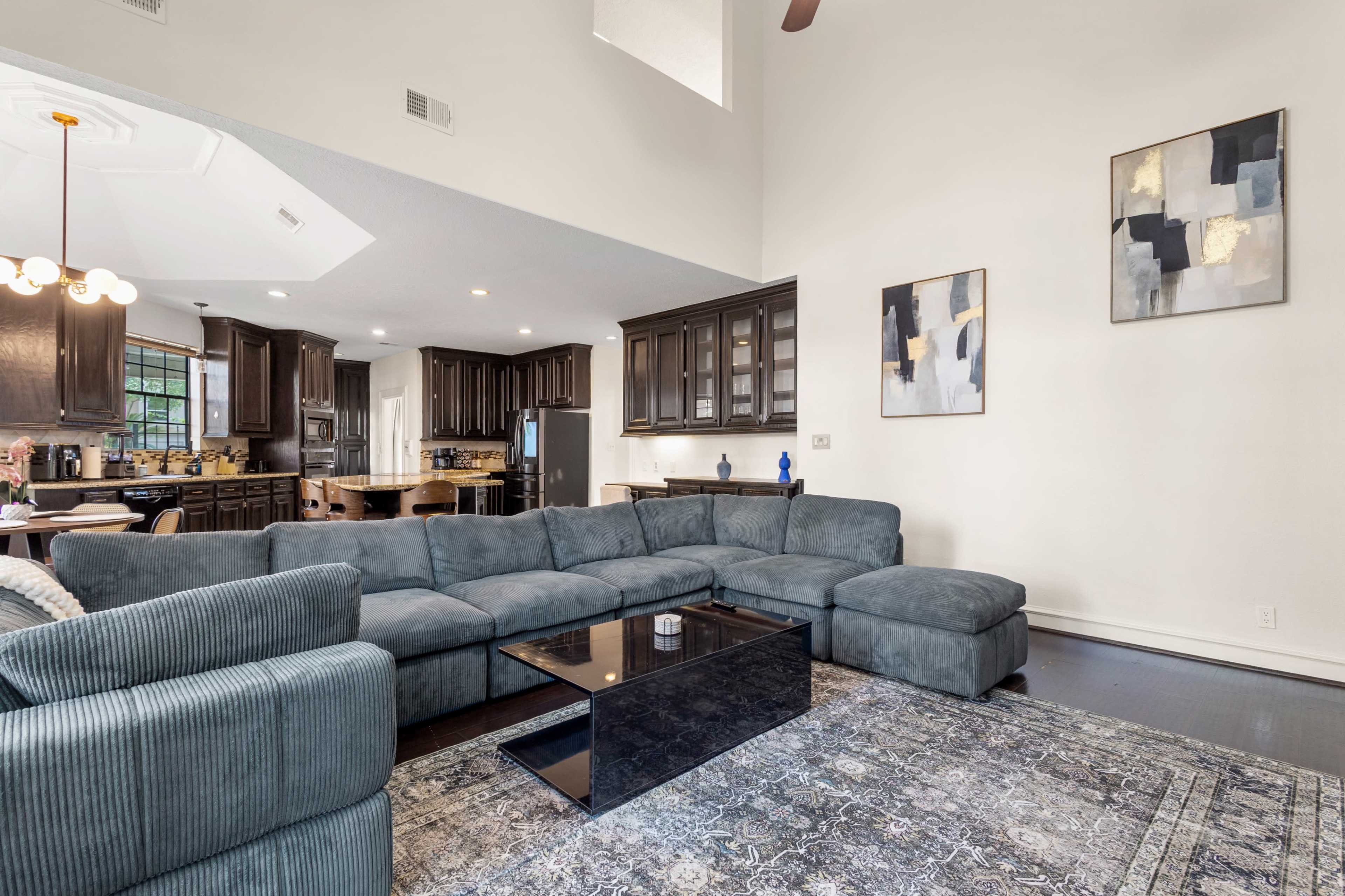 The image shows a living room with a large gray sectional sofa, a black coffee table, and modern artwork on the walls.