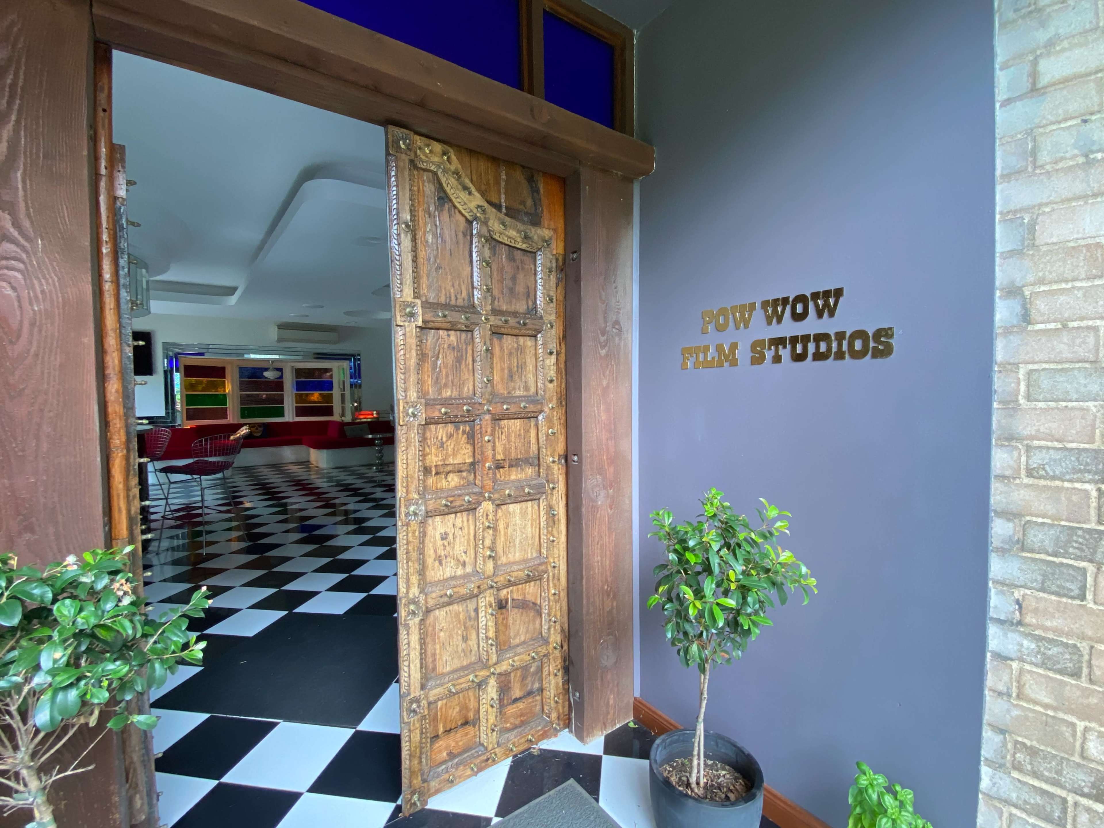 The entrance to Pow Wow Film Studios features a rustic wooden door open to reveal a black and white checkered floor inside.
