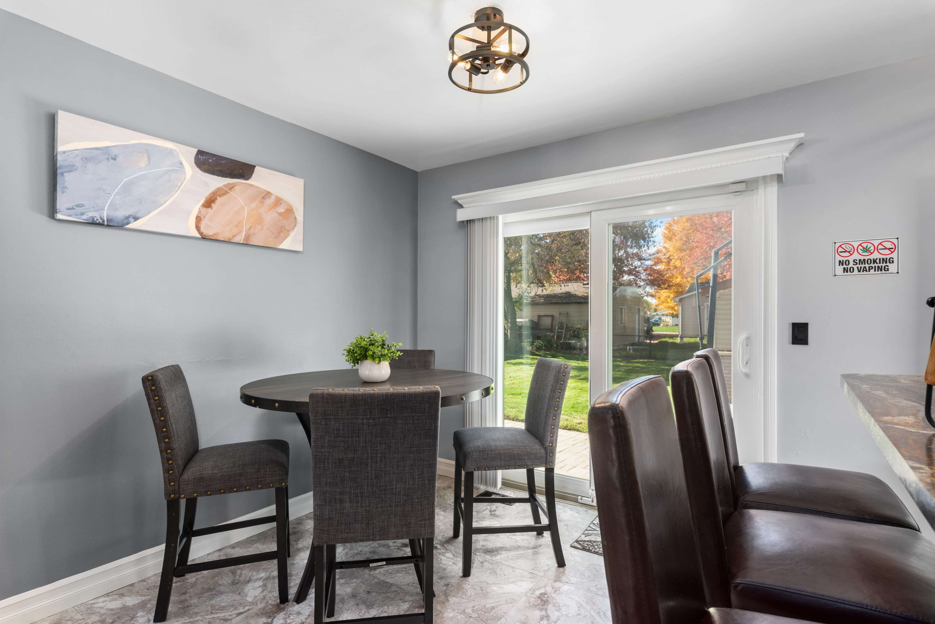 A small dining area features a round table surrounded by four chairs, with a sliding glass door leading to an outdoor space.