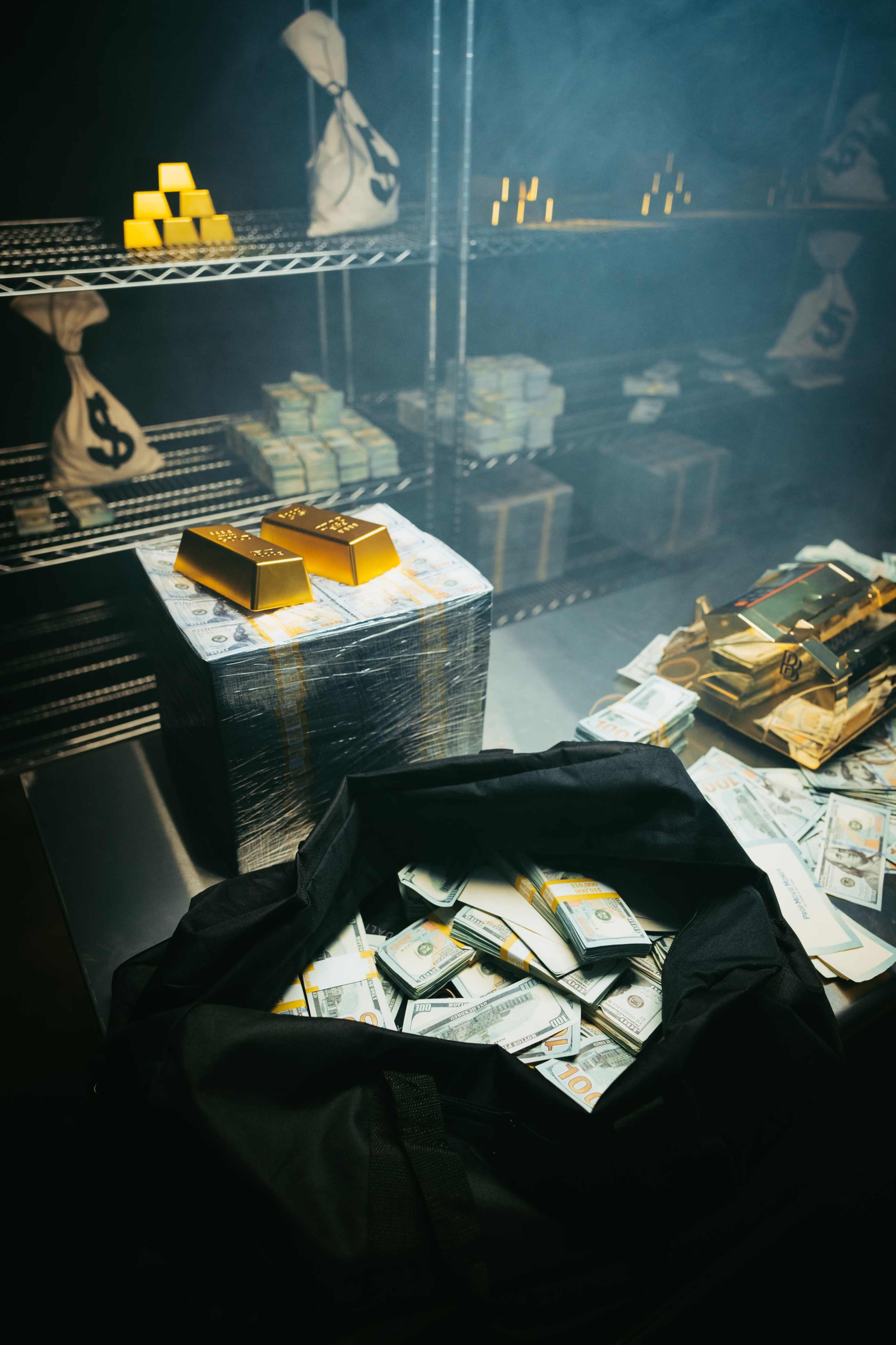 The image shows stacks of cash and gold bars in a dimly lit room, with bags containing money on shelves in the background.