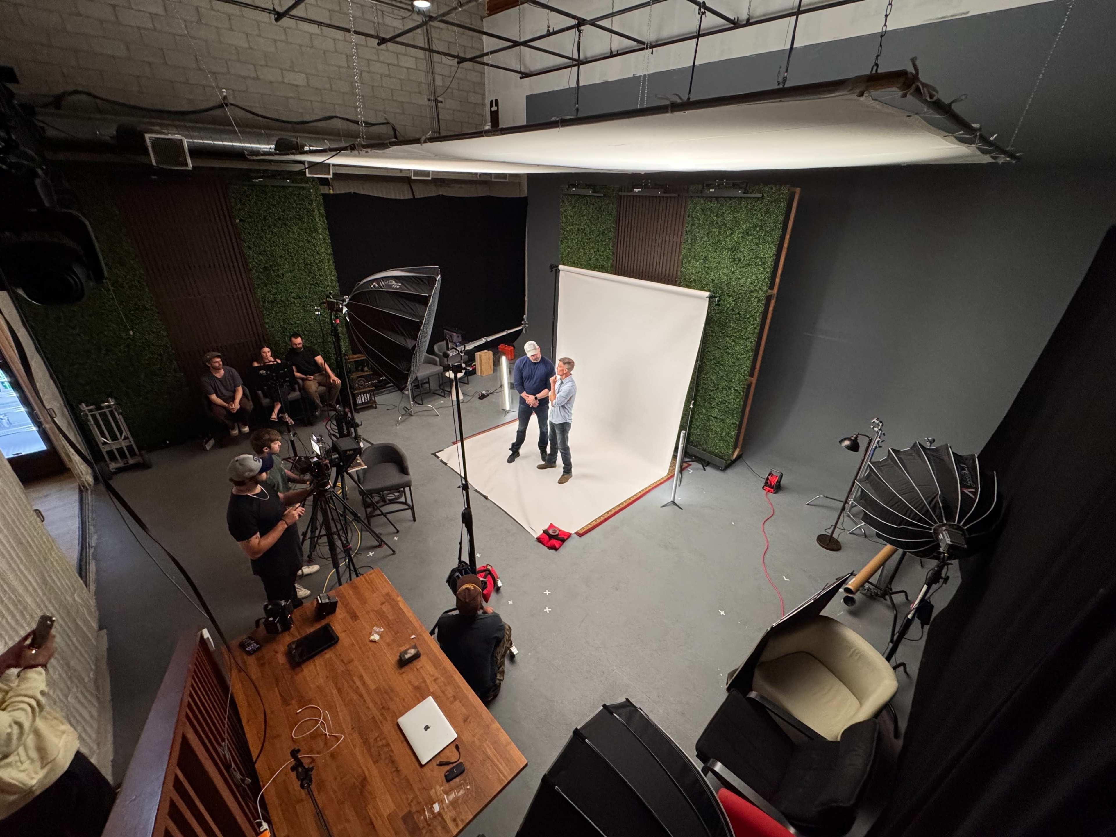 A photography studio is set up with a backdrop, lighting equipment, and a group of people preparing for a shoot.
