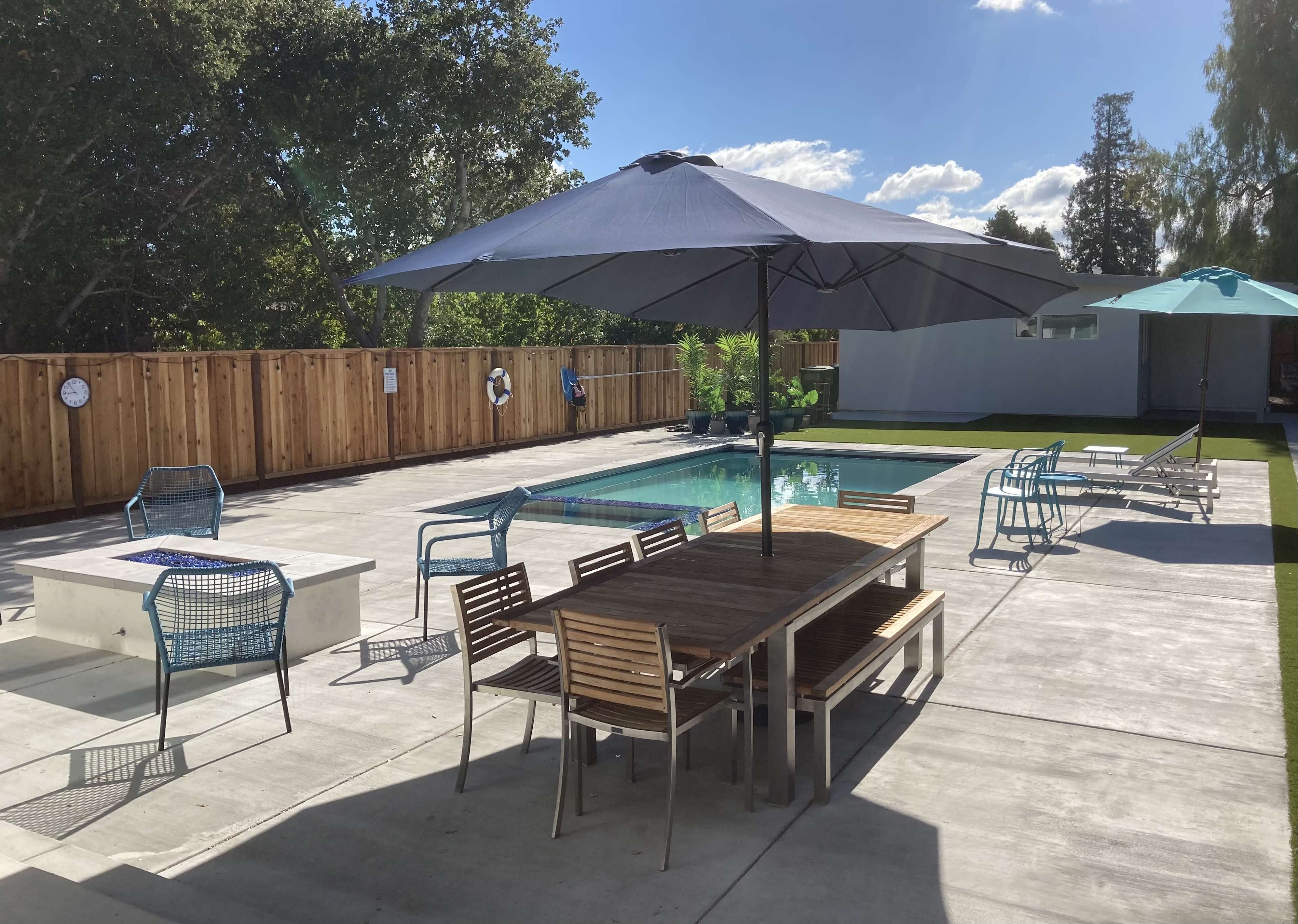 A spacious outdoor area with a swimming pool, lounge chairs, and a table under a large umbrella.