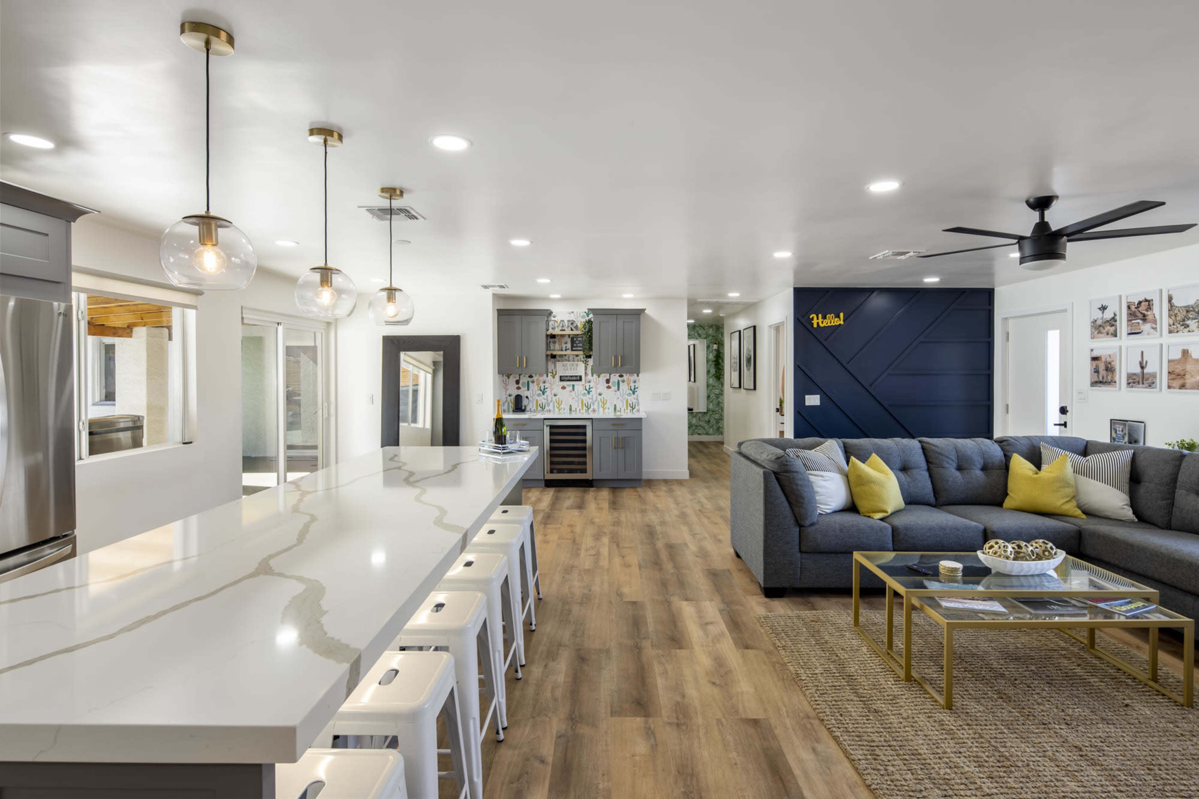 A modern open-concept living area featuring a spacious kitchen island with seating, a cozy sectional sofa, and decorative elements on the walls.