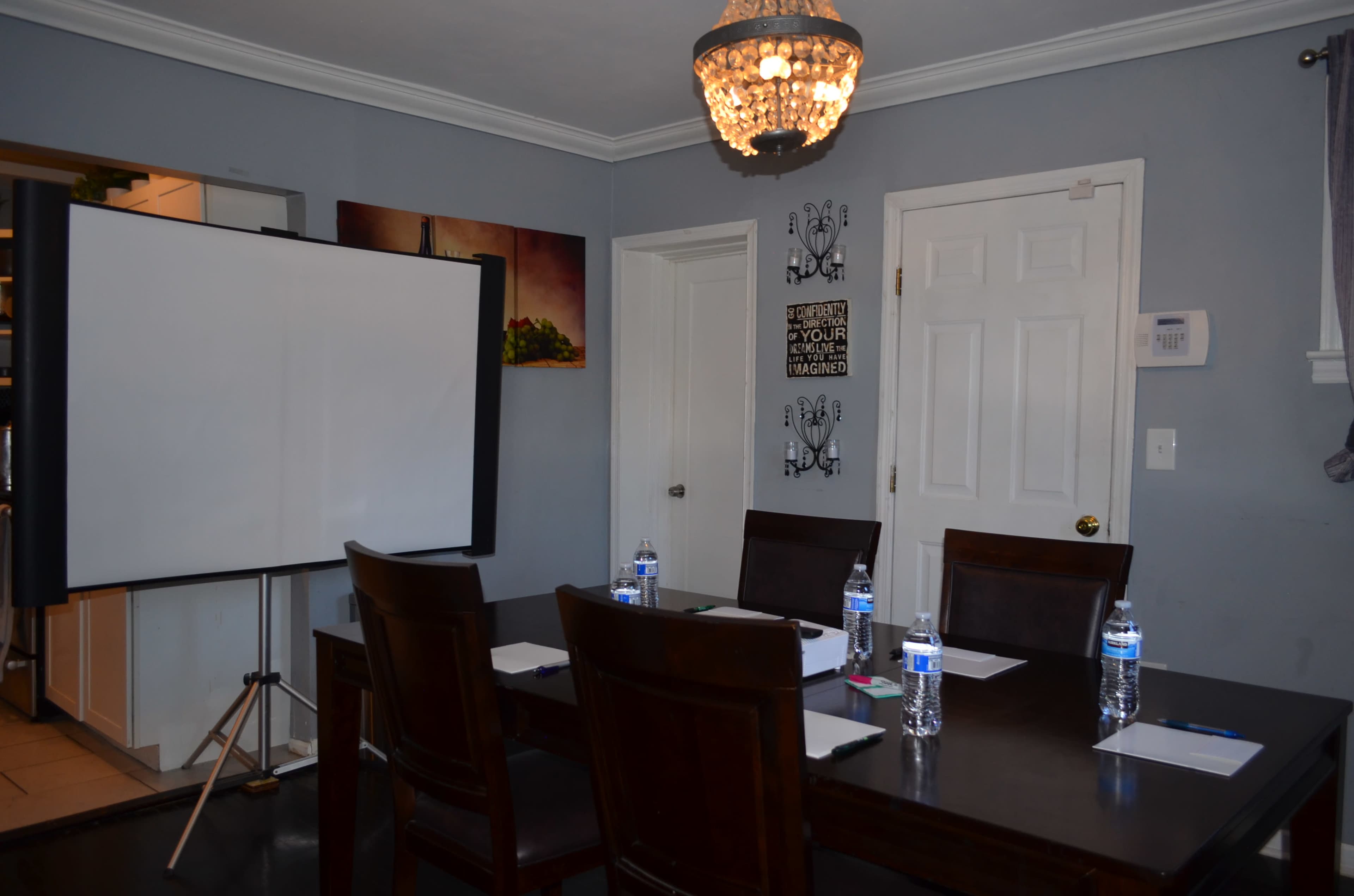 A conference room is set up with a large table, chairs, a flip chart, and water bottles on a dark wooden table.