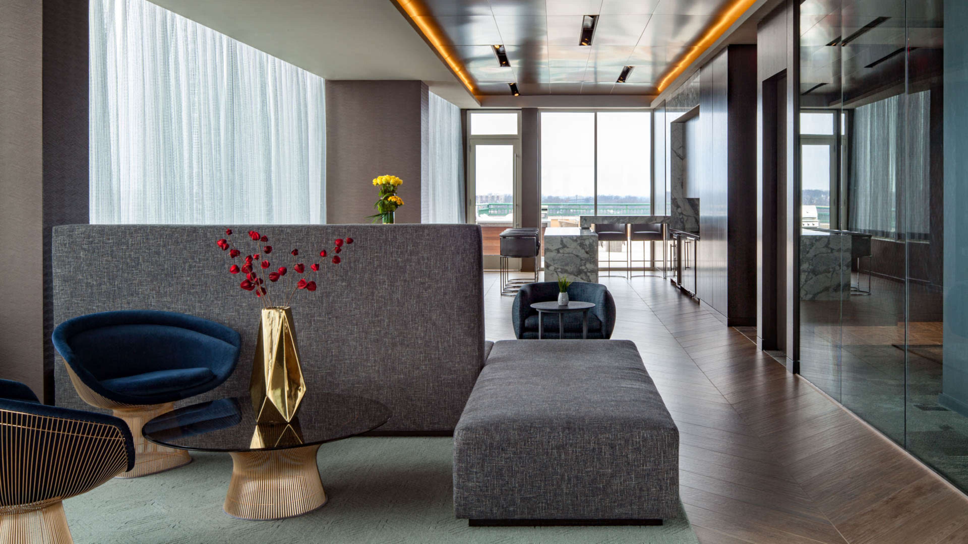 A modern, elegantly designed waiting area featuring a gray partition, contemporary furniture, and large windows with a view.