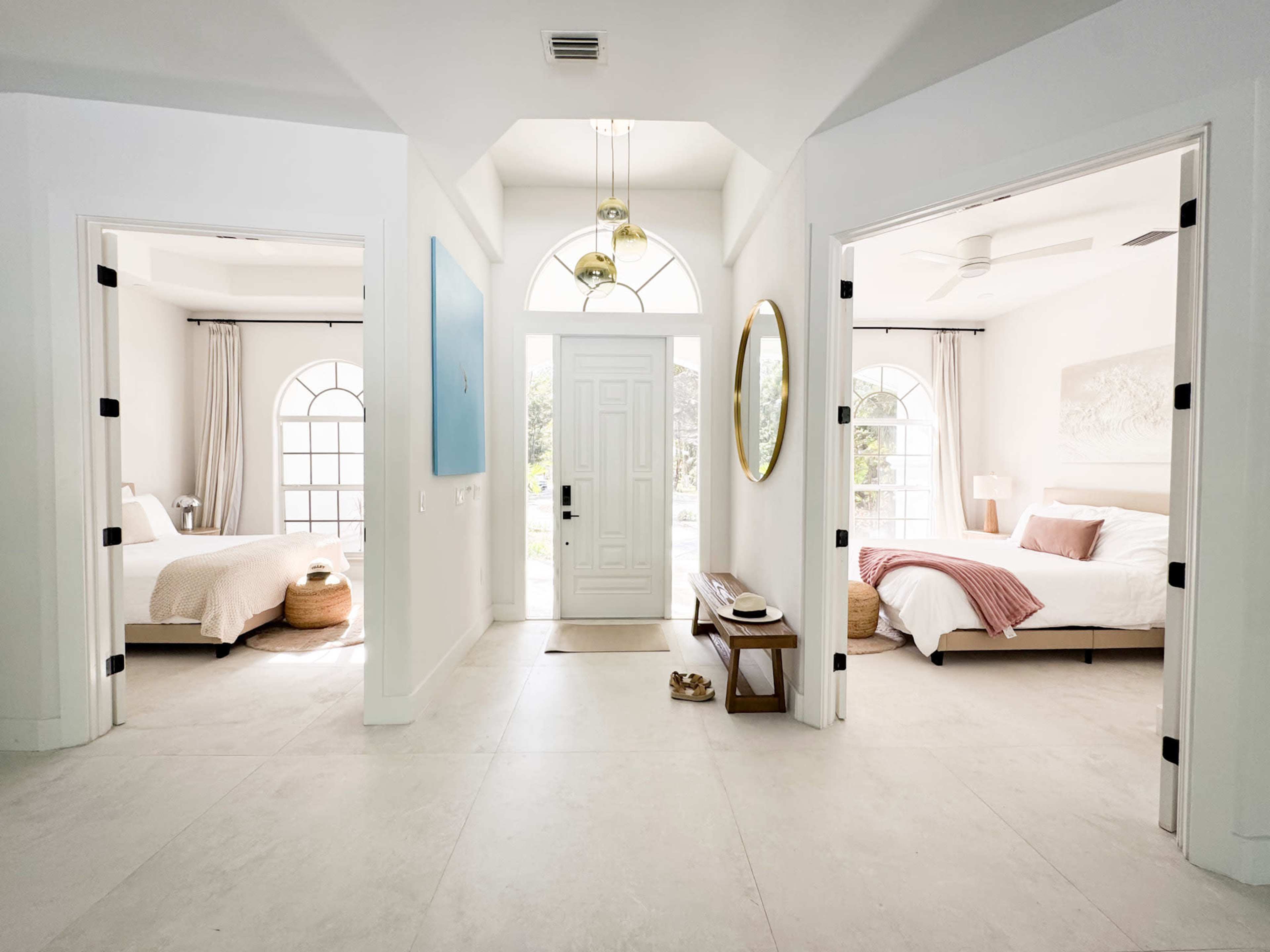 The image shows a hallway with an entrance door and two bedrooms on either side, featuring light-colored walls and simple furnishings.