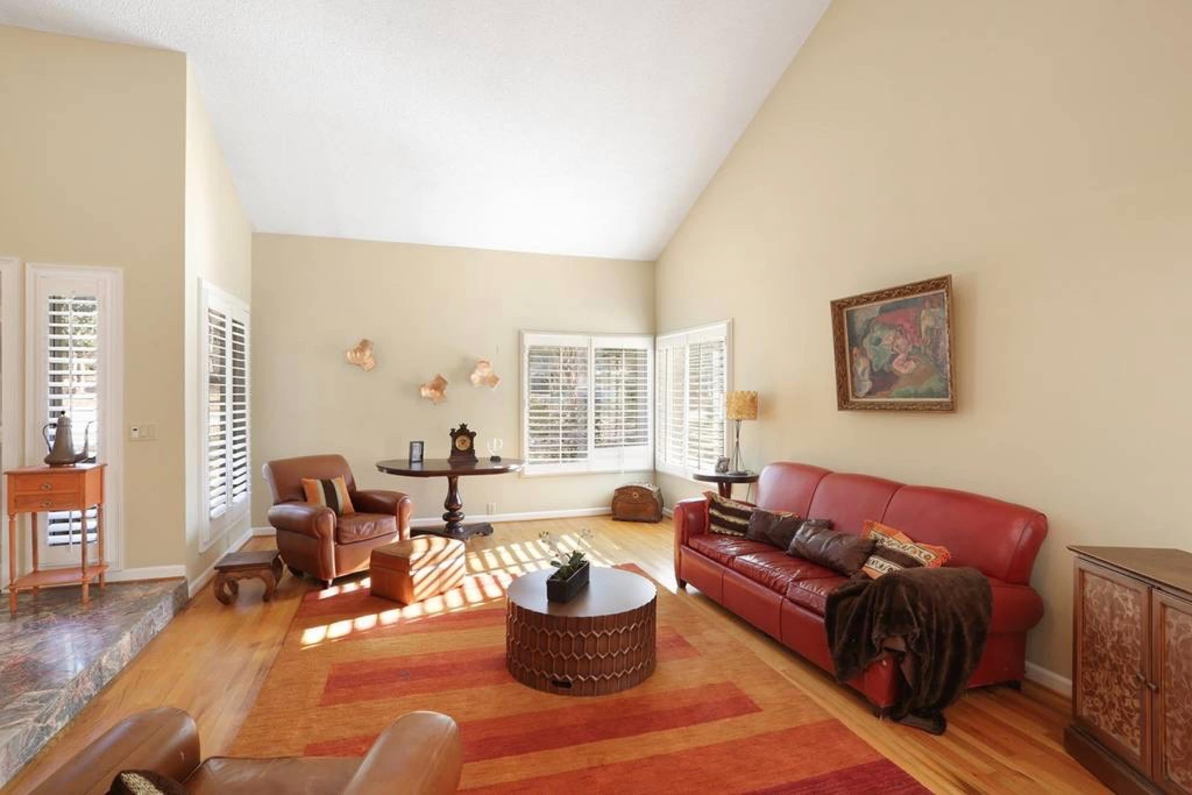 The living room features a red sofa, a coffee table, and large windows allowing natural light to illuminate the space.