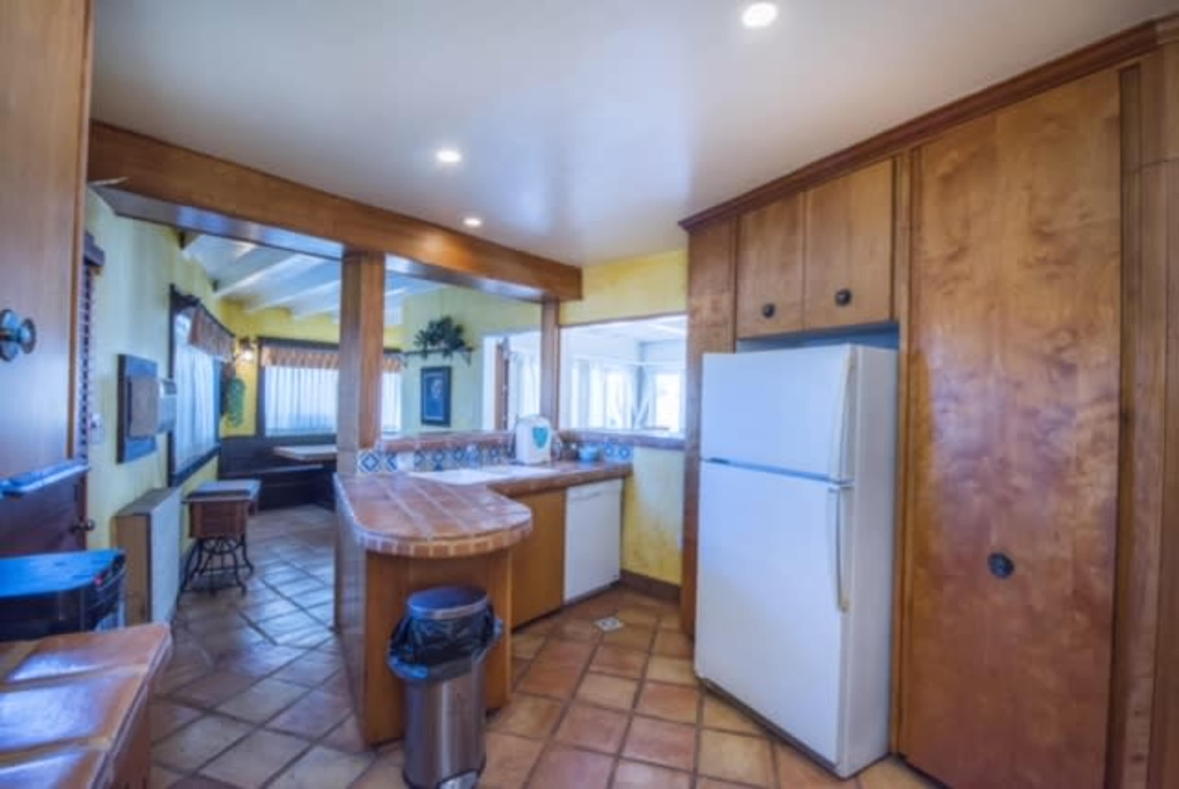 A kitchen featuring wooden cabinetry, a white refrigerator, and tiled flooring with a small table area.