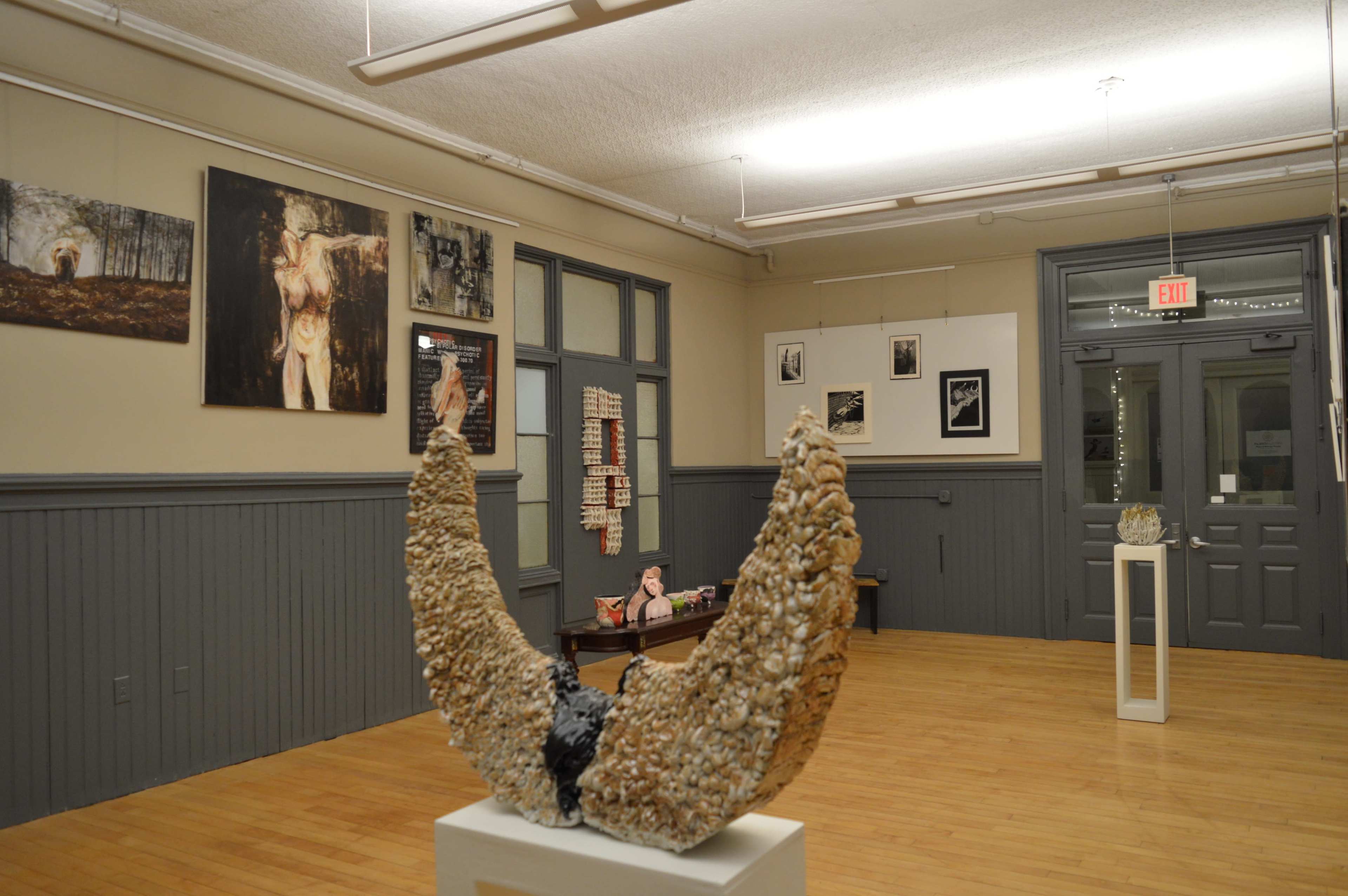 An art gallery interior featuring sculptures and various framed artworks displayed on the walls.