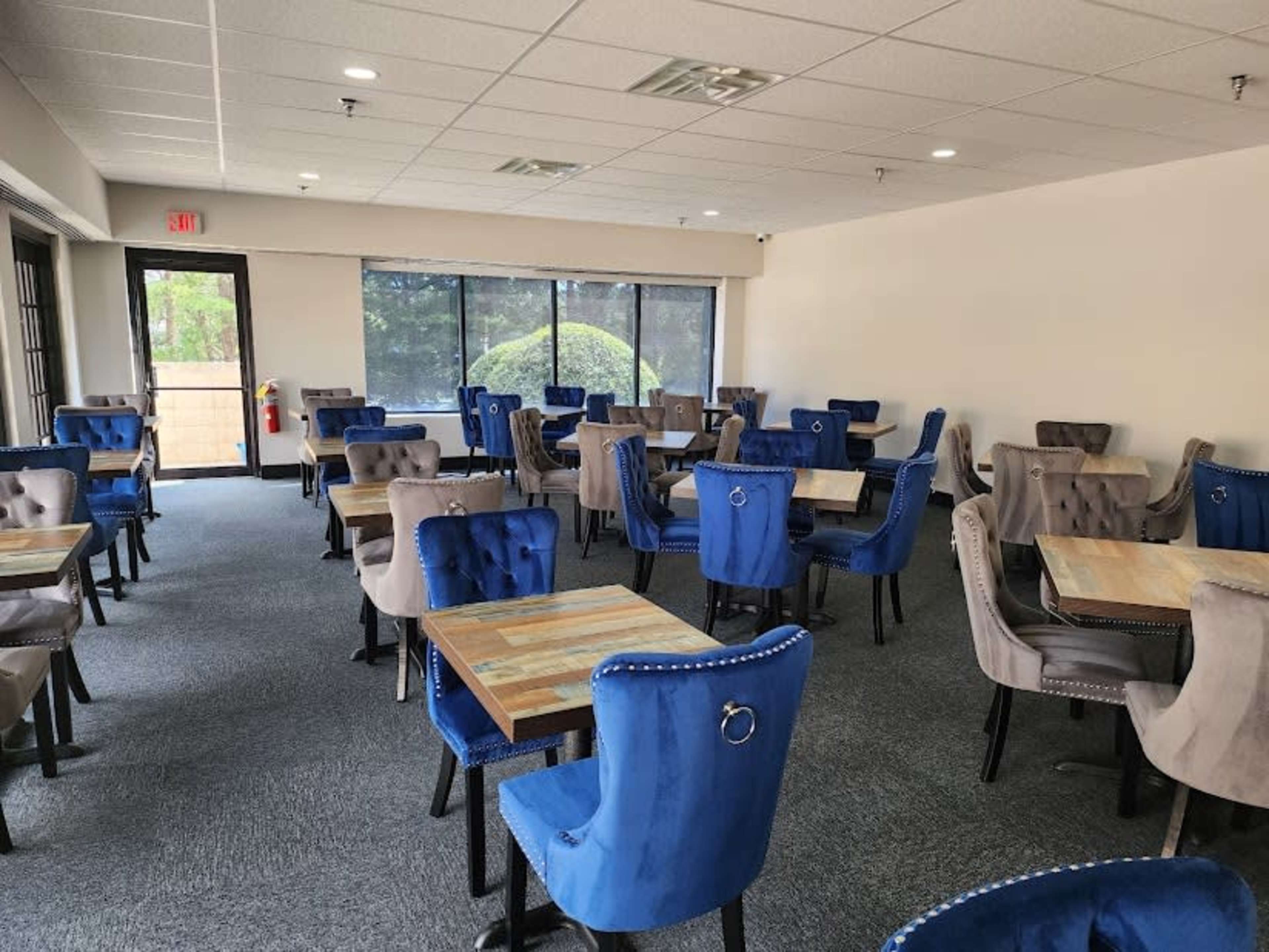 A spacious dining area with multiple blue and gray upholstered chairs around wooden tables.