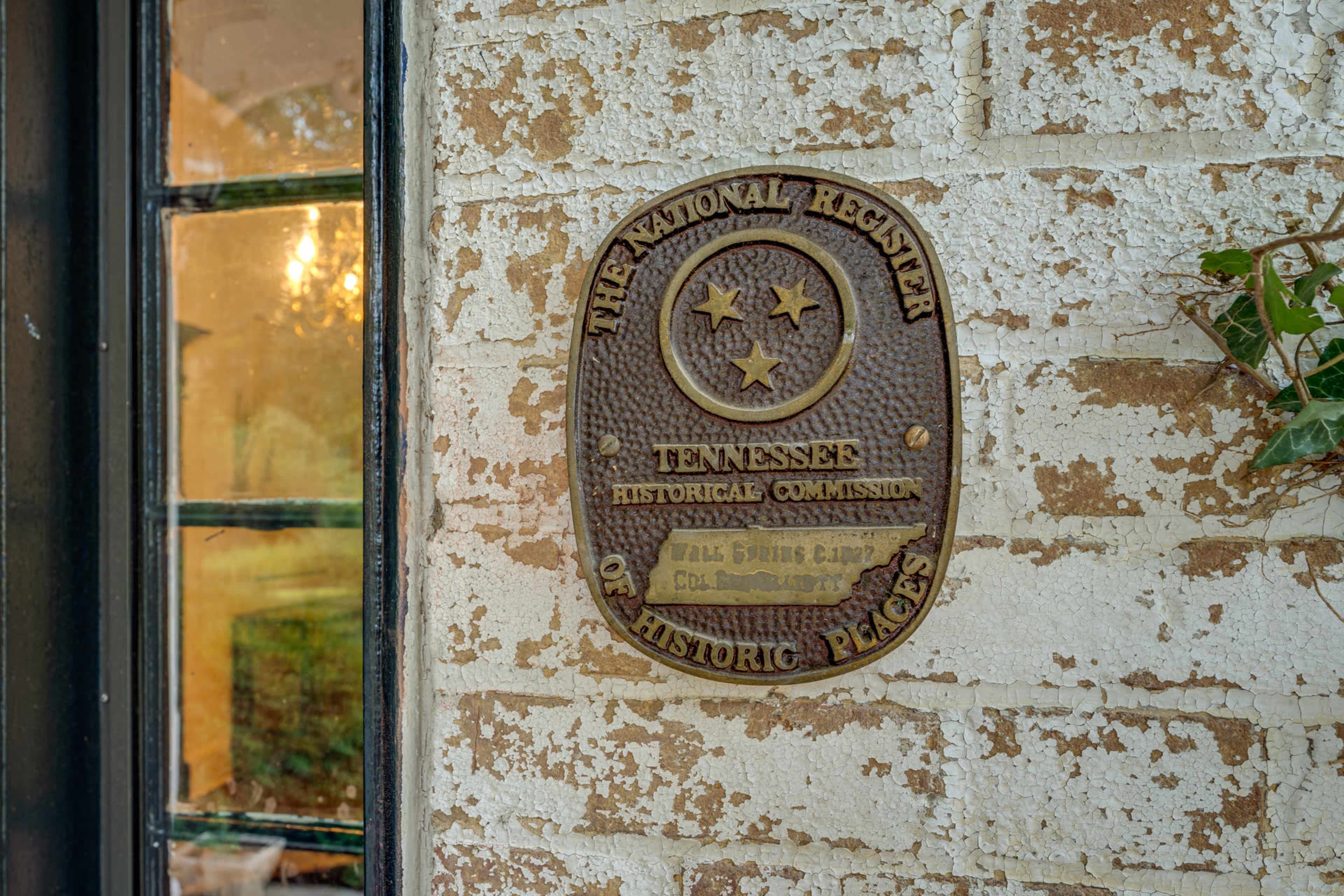 A bronze plaque mounted on a brick wall, indicating the property is listed on the National Register of Historic Places in Tennessee.