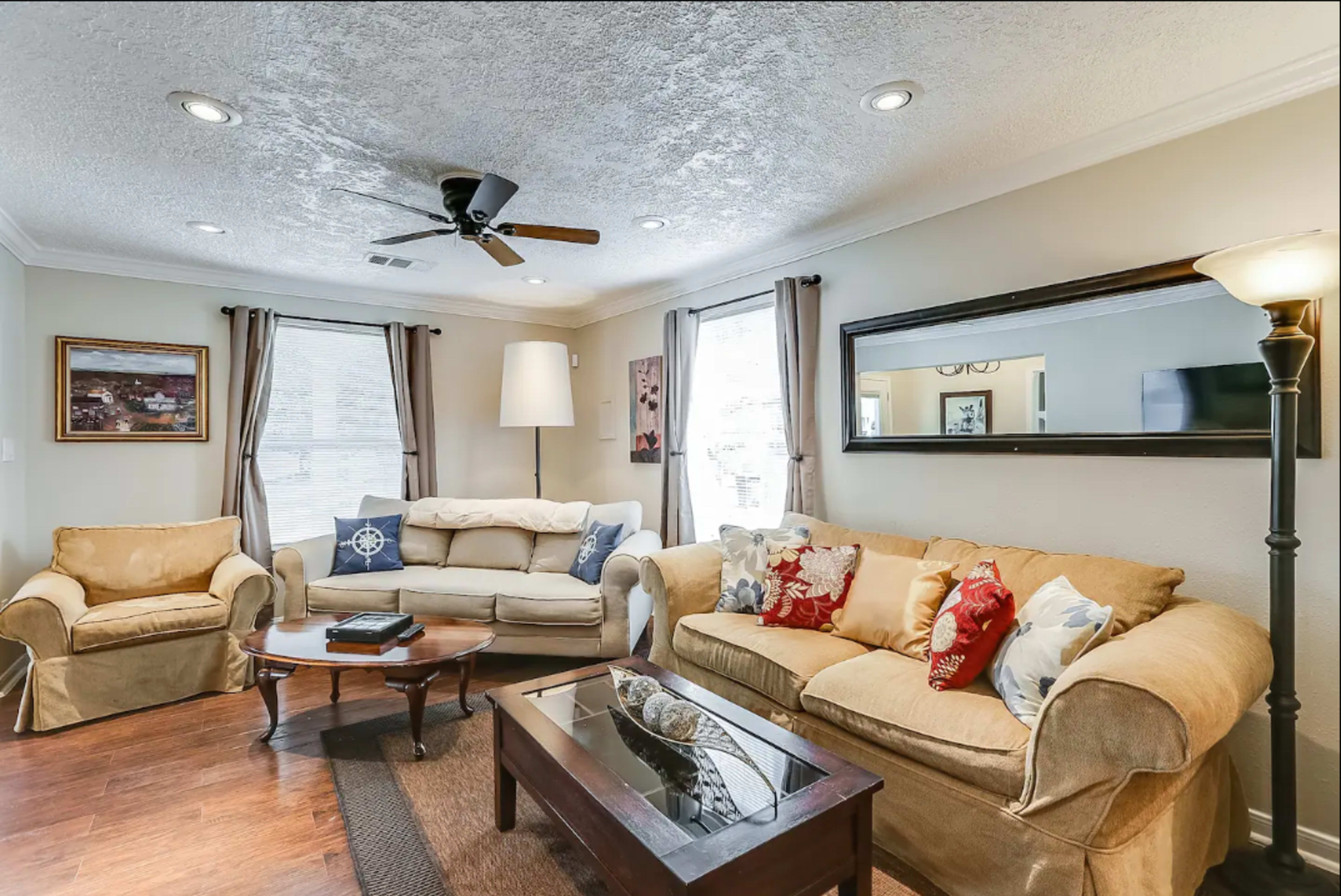 A living room furnished with two sofas, a coffee table, a lamp, and framed artwork on the walls.