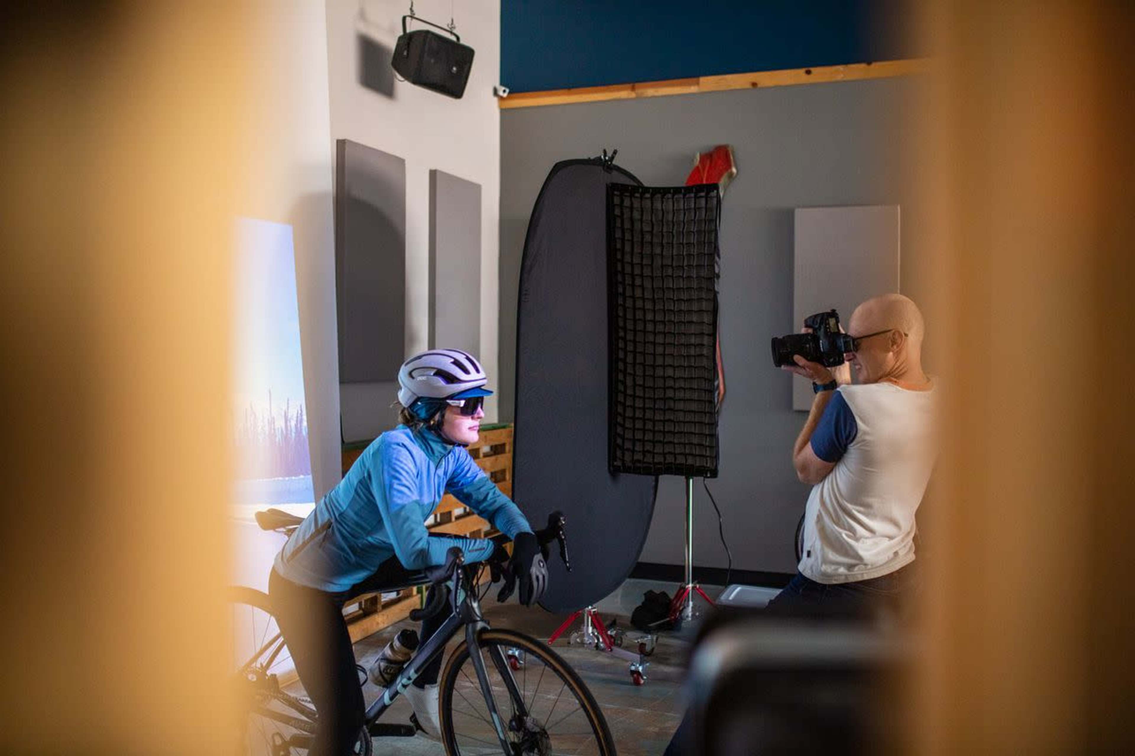 A photographer captures an athlete on a bicycle in a studio setting.