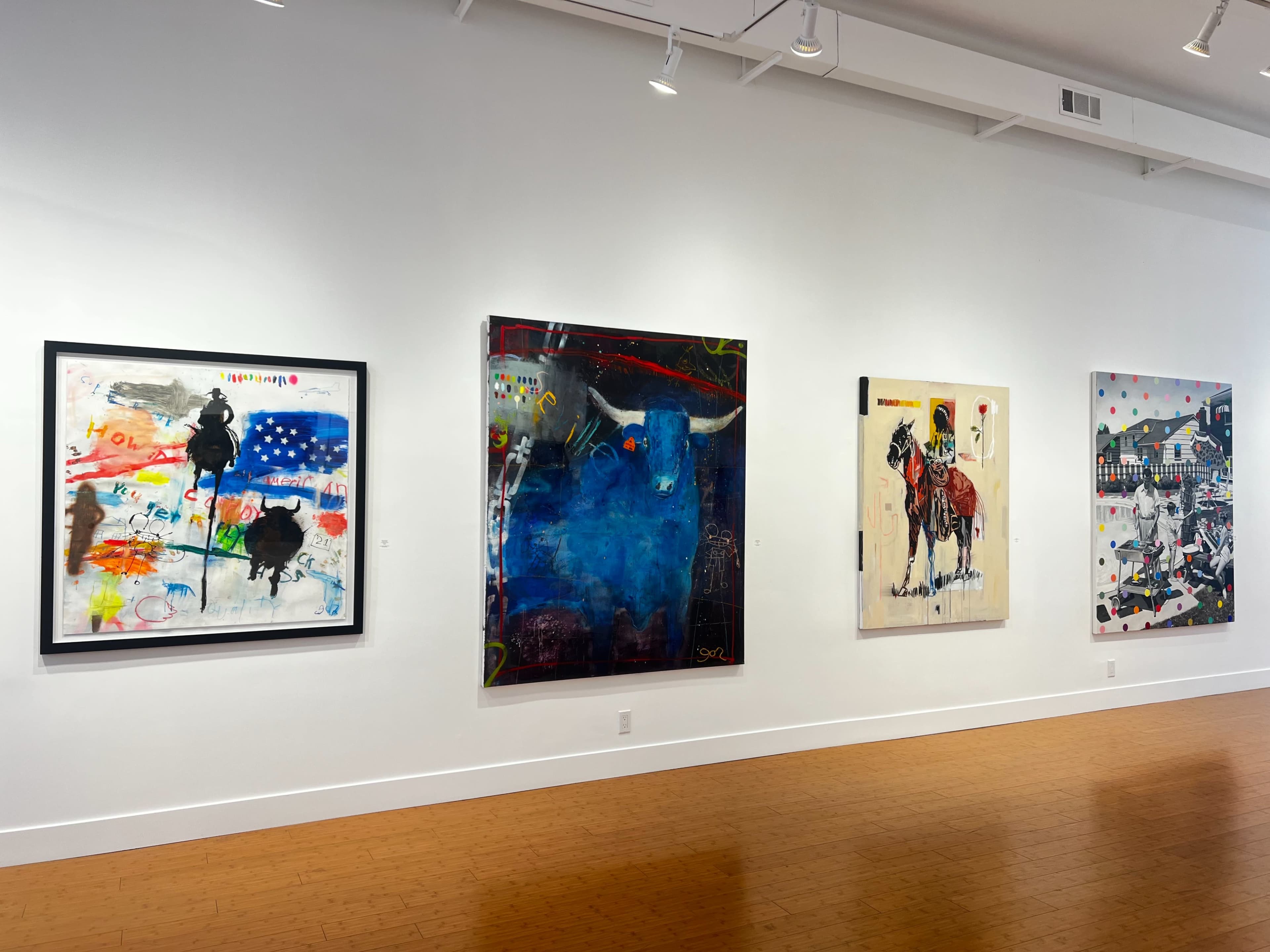 The image shows a gallery wall displaying four colorful abstract artworks, each framed and featuring various themes and designs.