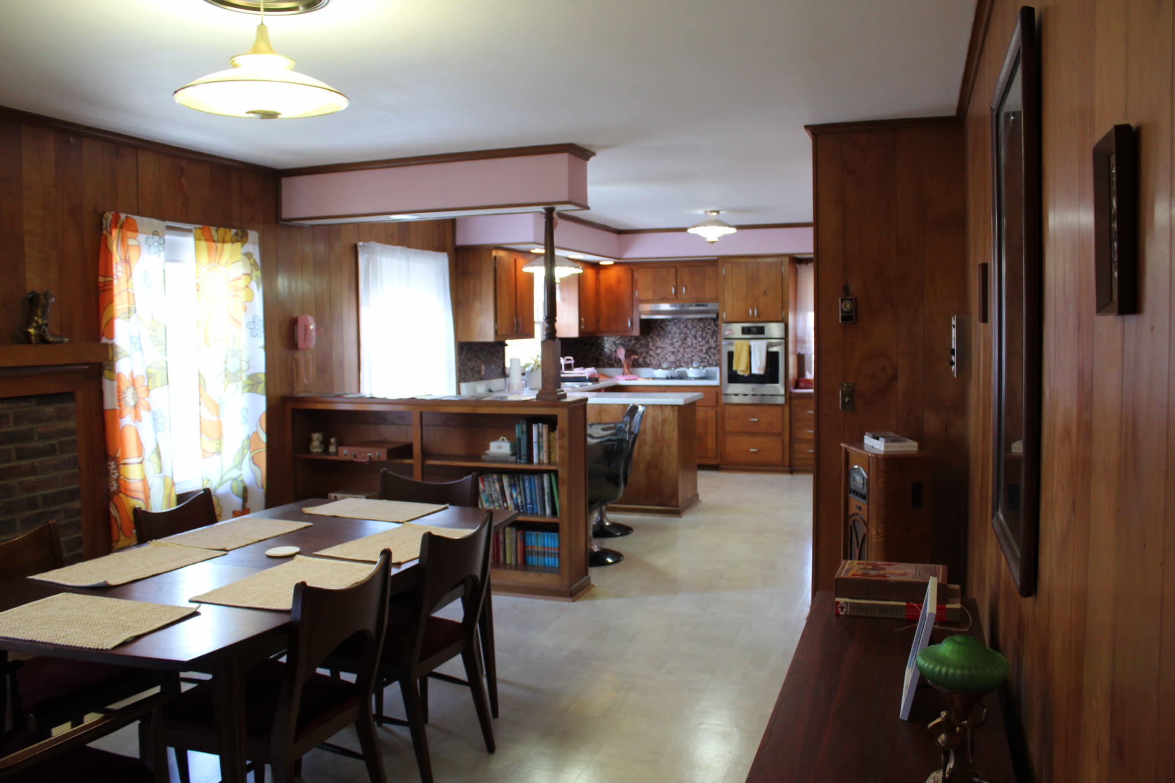 A spacious kitchen and dining area feature wooden paneling, a long table with chairs, and modern appliances.