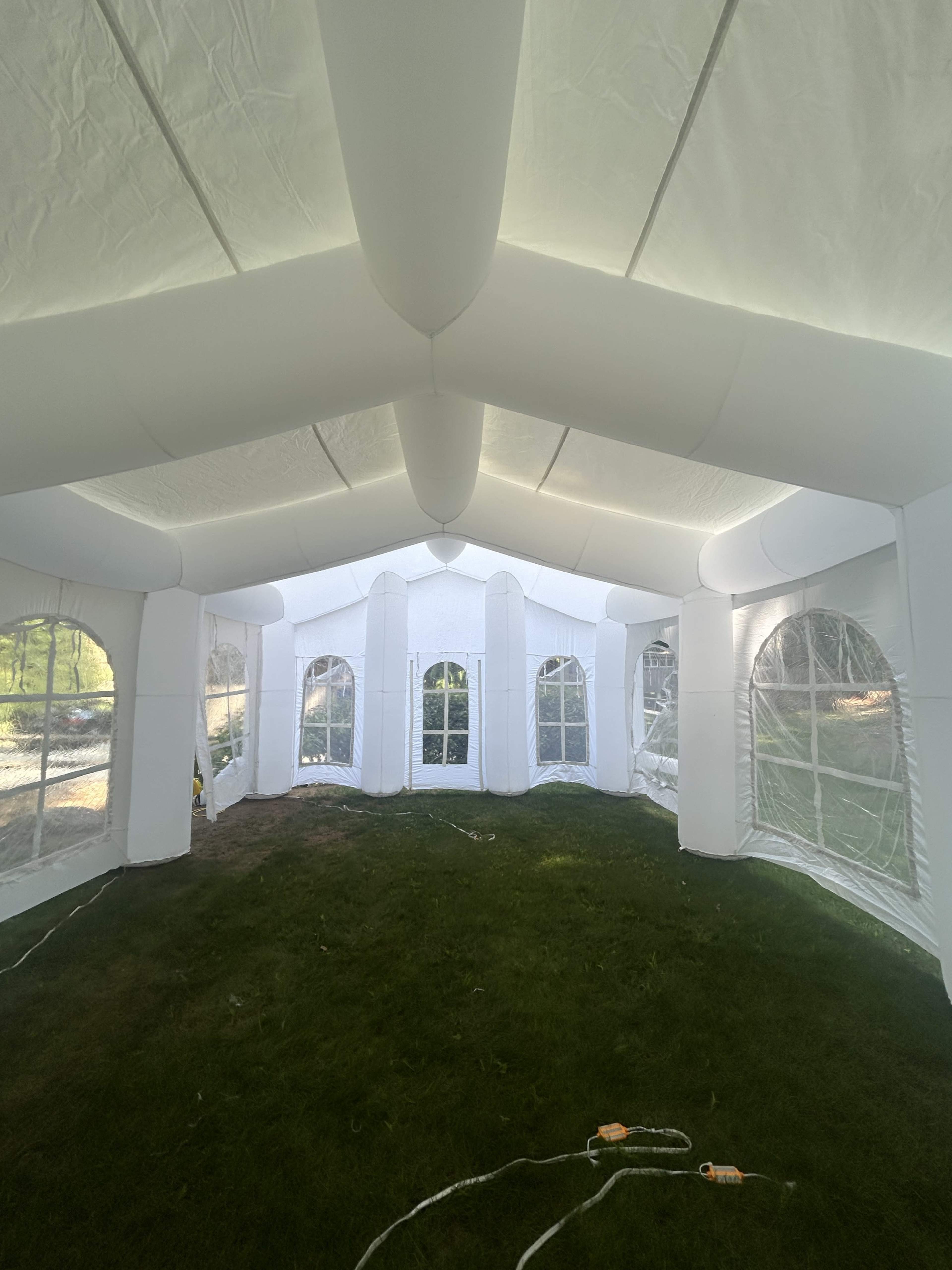 The image shows the interior of a large, white inflatable tent with multiple arched sections and windows.