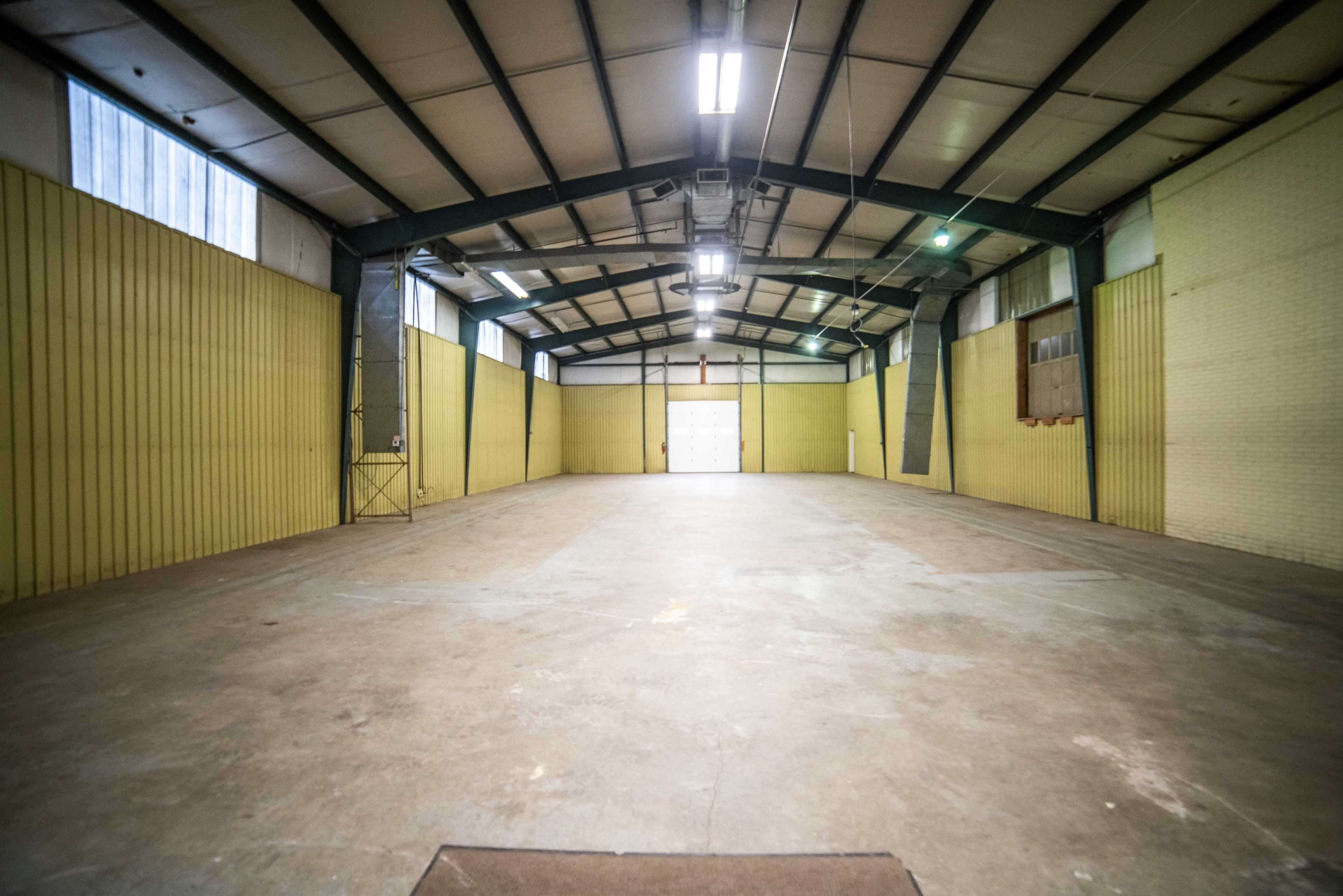 A large, empty industrial warehouse with yellow walls and a high ceiling.