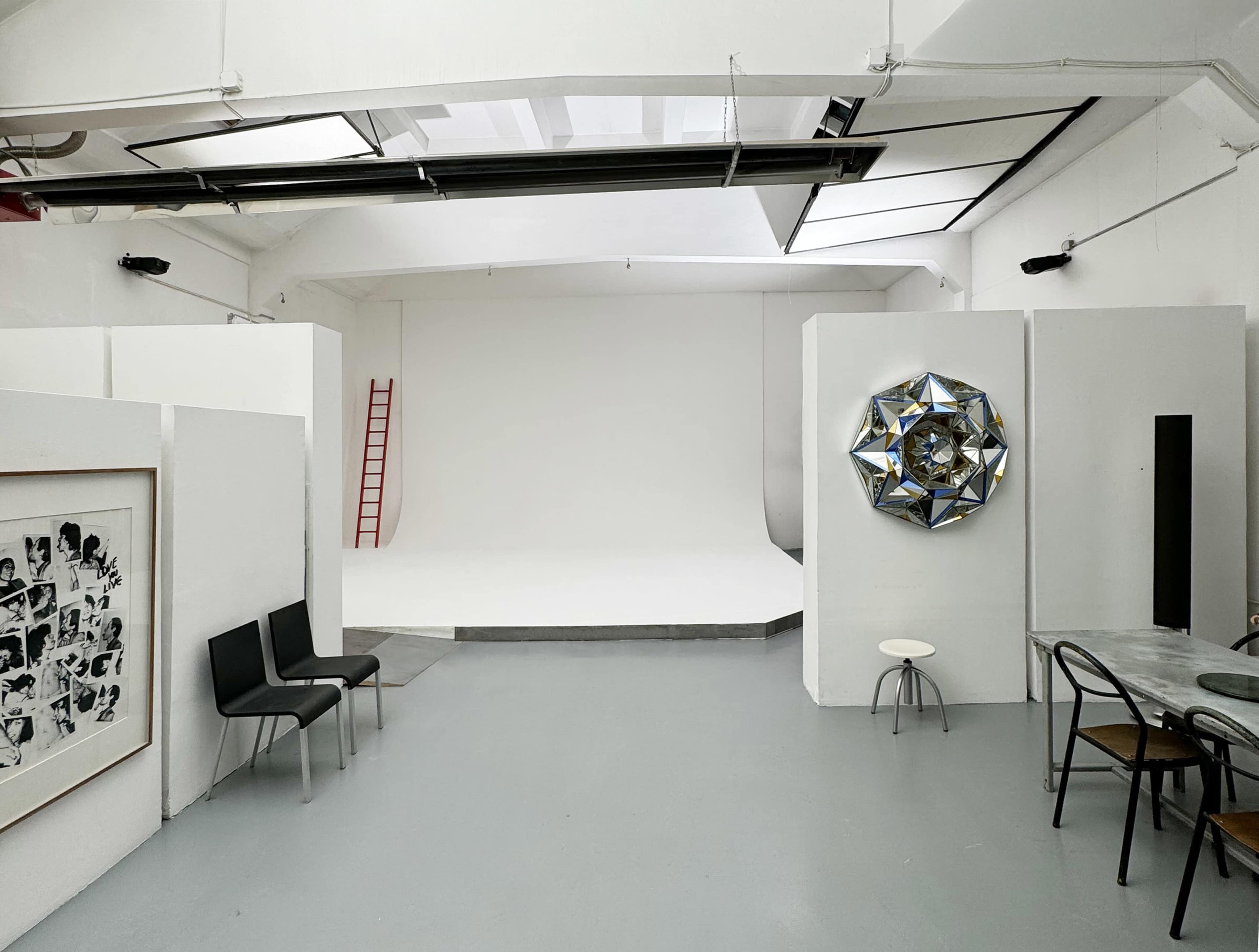 A spacious, minimalist studio with white walls, a simple furniture arrangement, and a clear backdrop for photography.