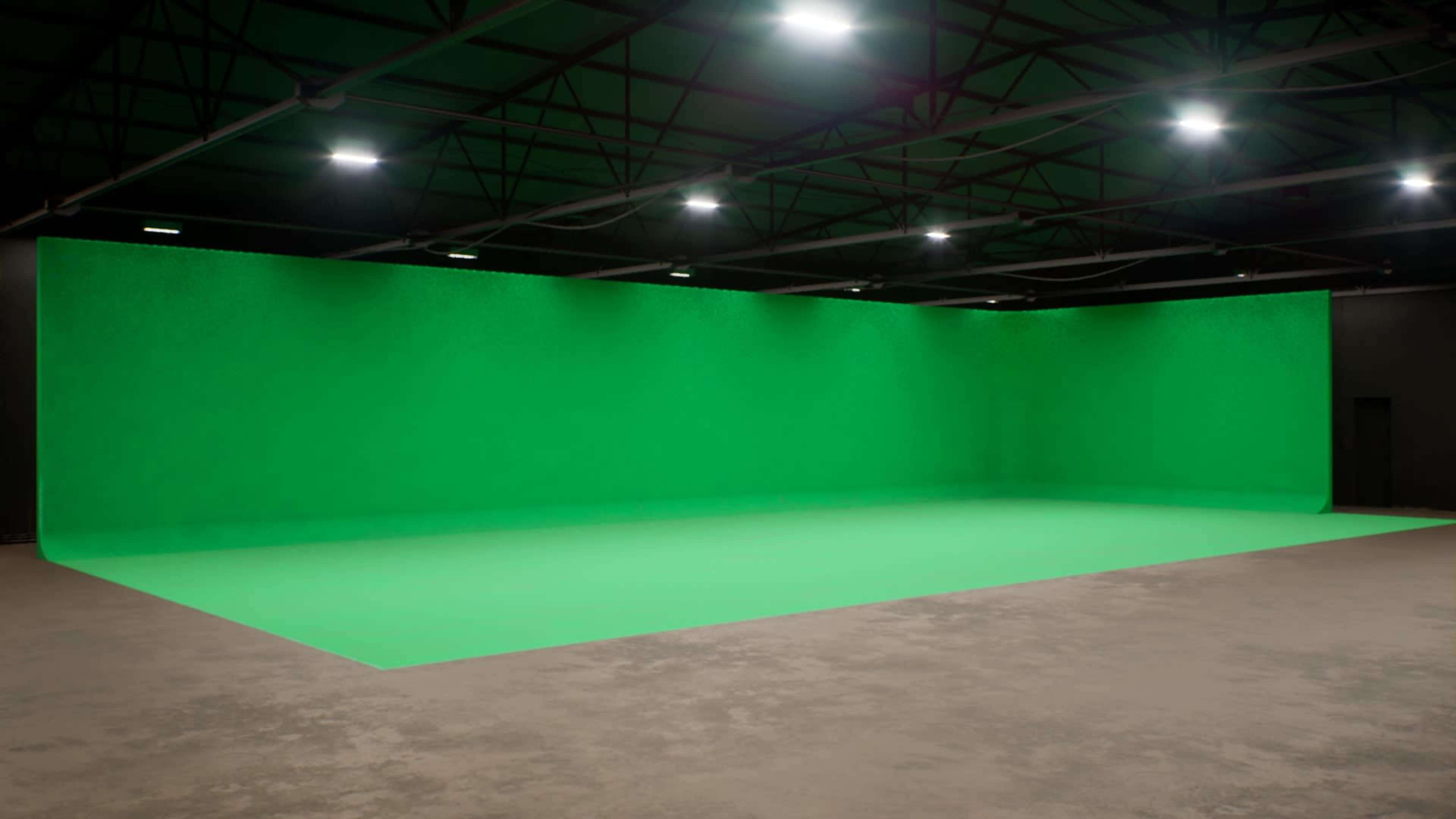 A large green screen setup in a spacious studio with overhead lighting.