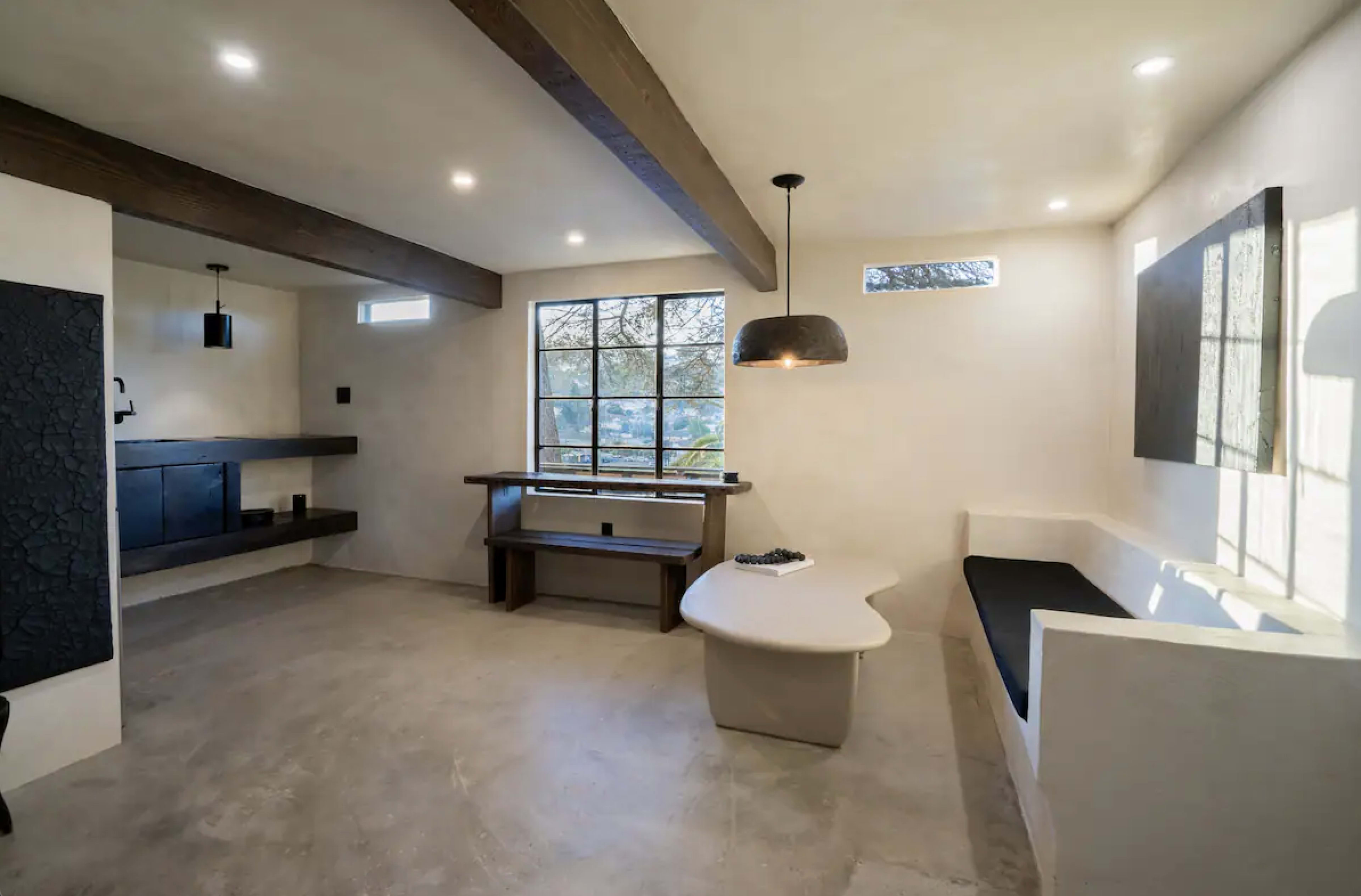 A modern interior living space featuring a neutral color palette, minimalist furniture, and large windows that allow natural light to enter.