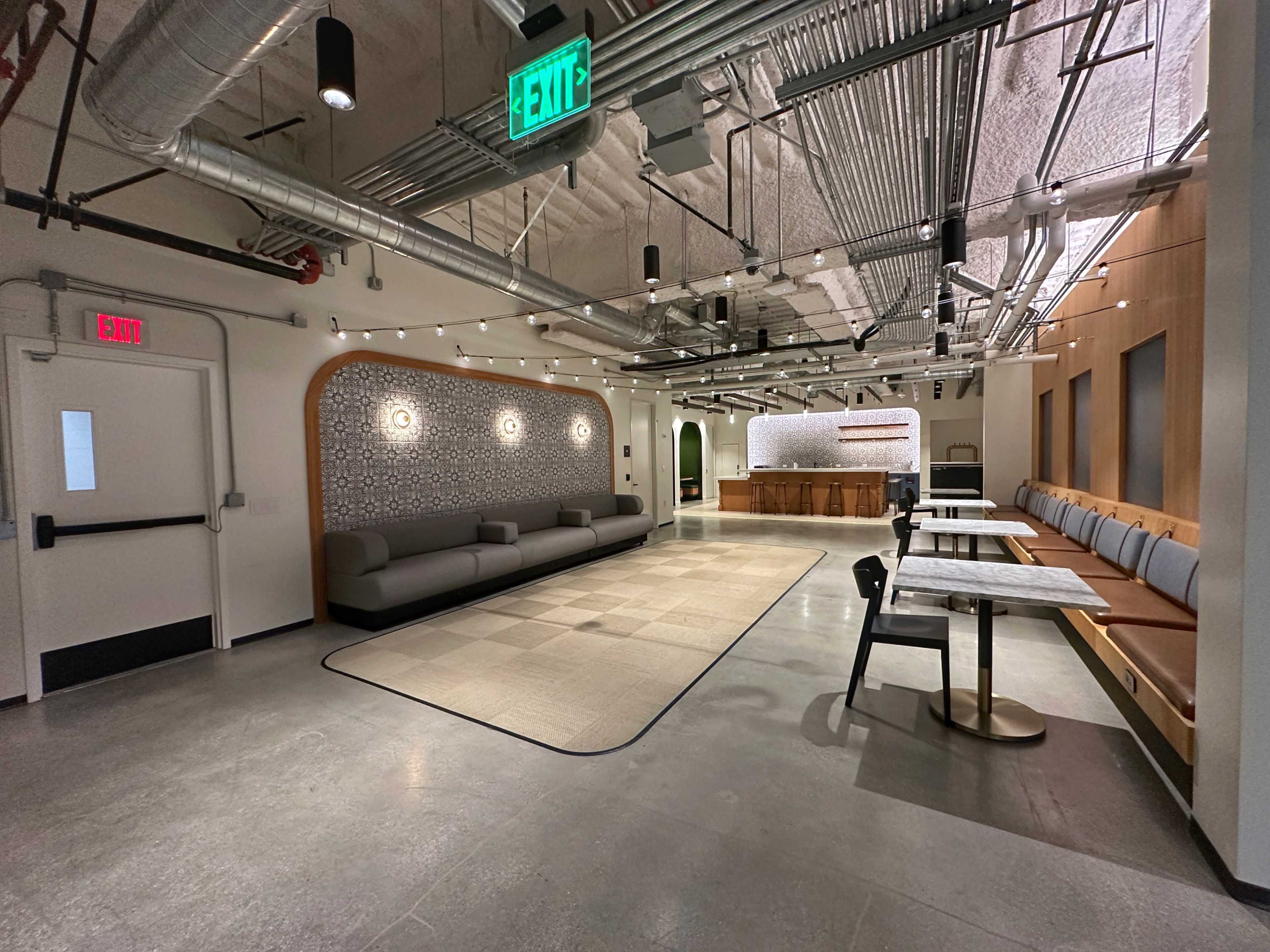 A modern, spacious interior of a communal area with seating, a service counter, and gray flooring.