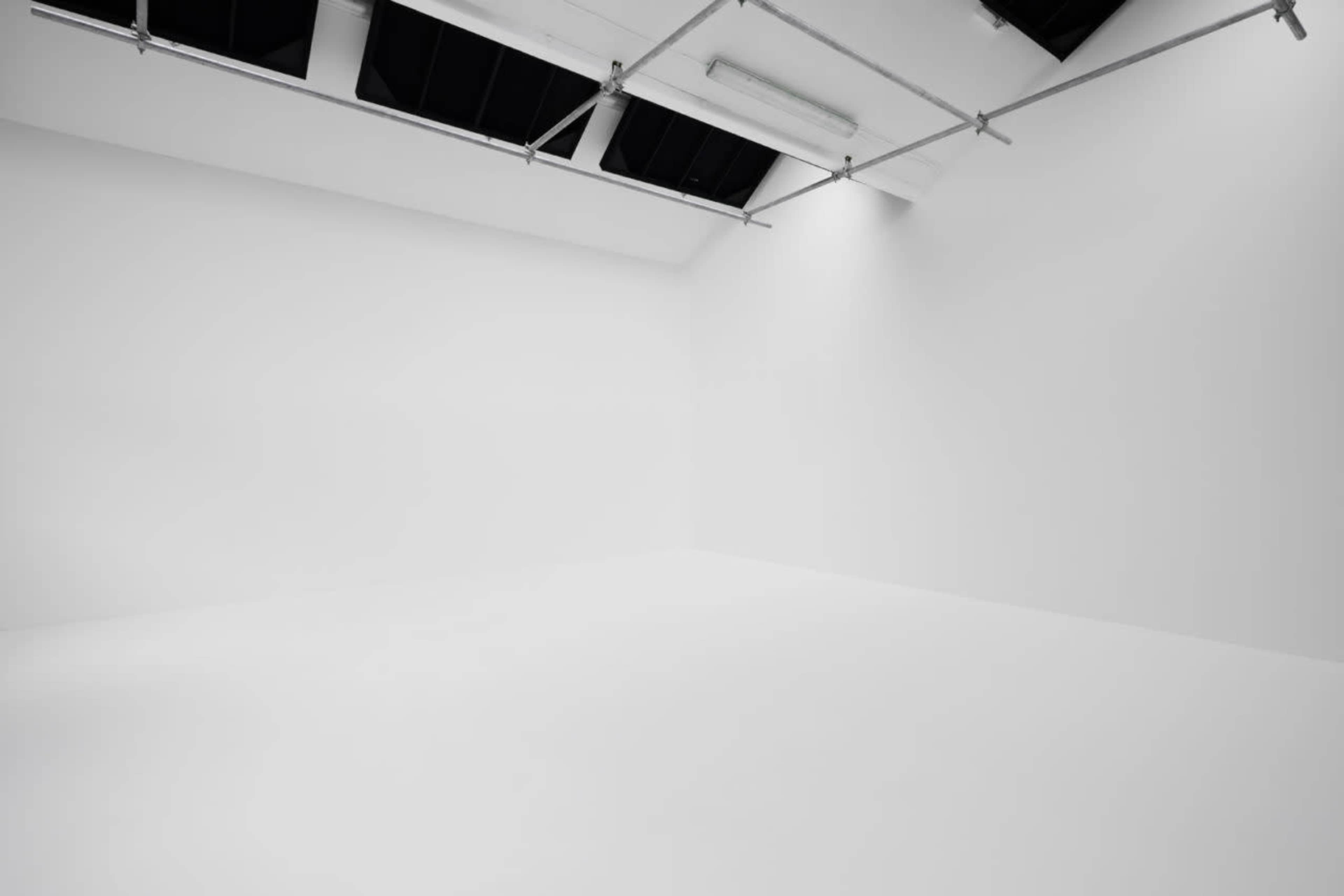 An empty, well-lit room with white walls and a flat white floor.
