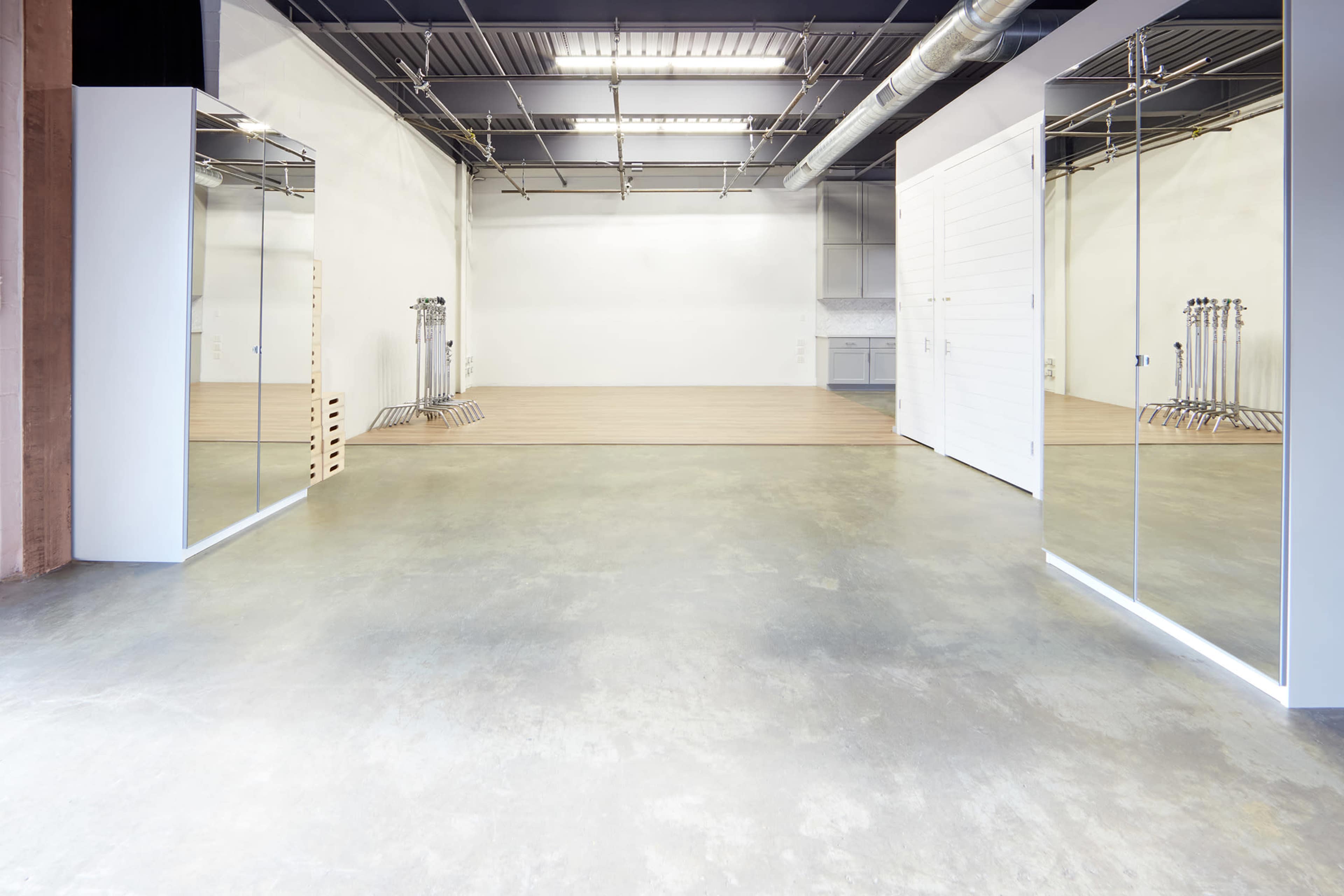 A spacious, empty interior with polished concrete floors and large mirrors on the walls.