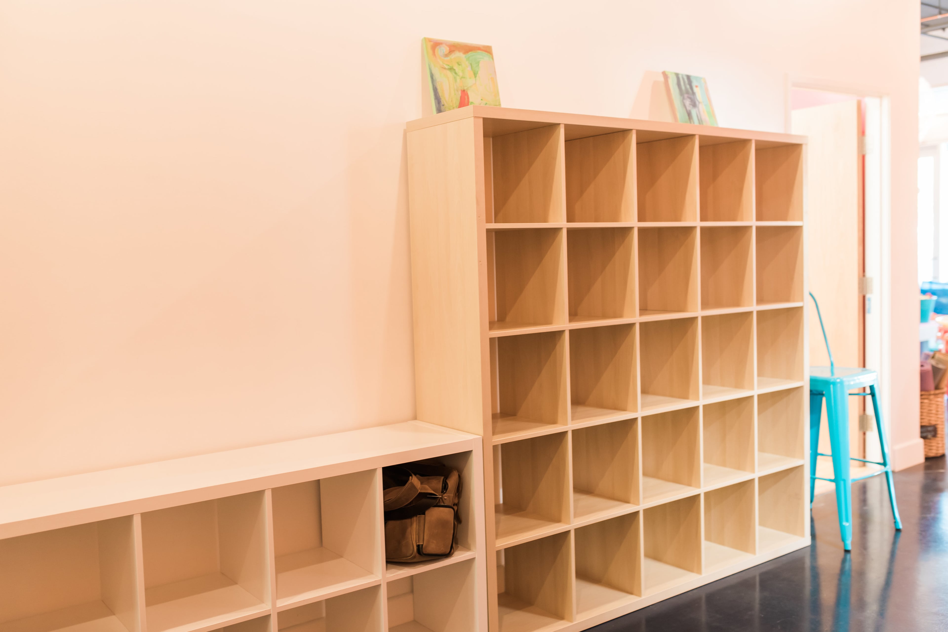 A bright interior space with two wooden cubed shelving units against a white wall.