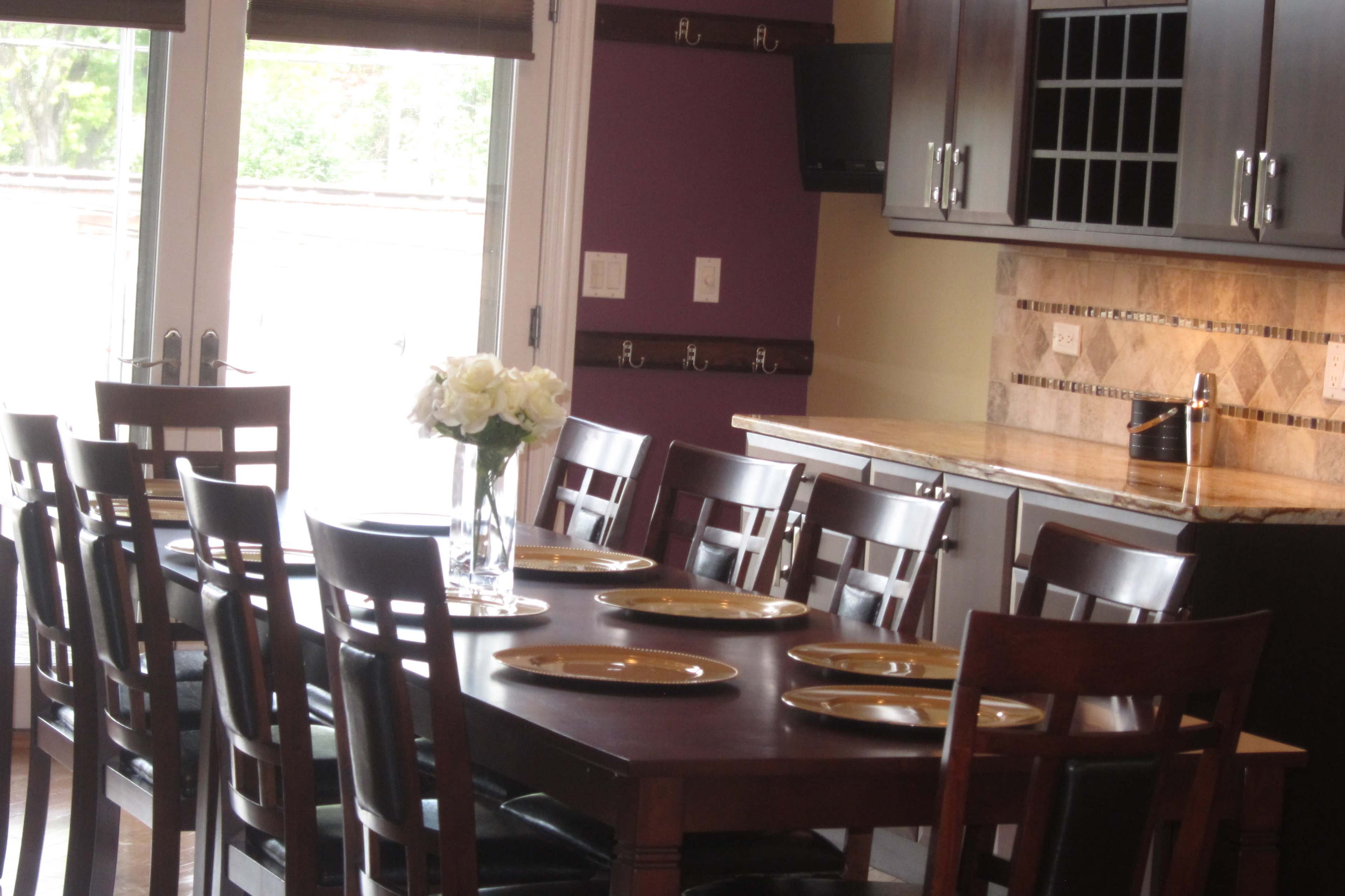 A dining table set for a meal is arranged in a modern kitchen with a vase of white flowers and empty plates.