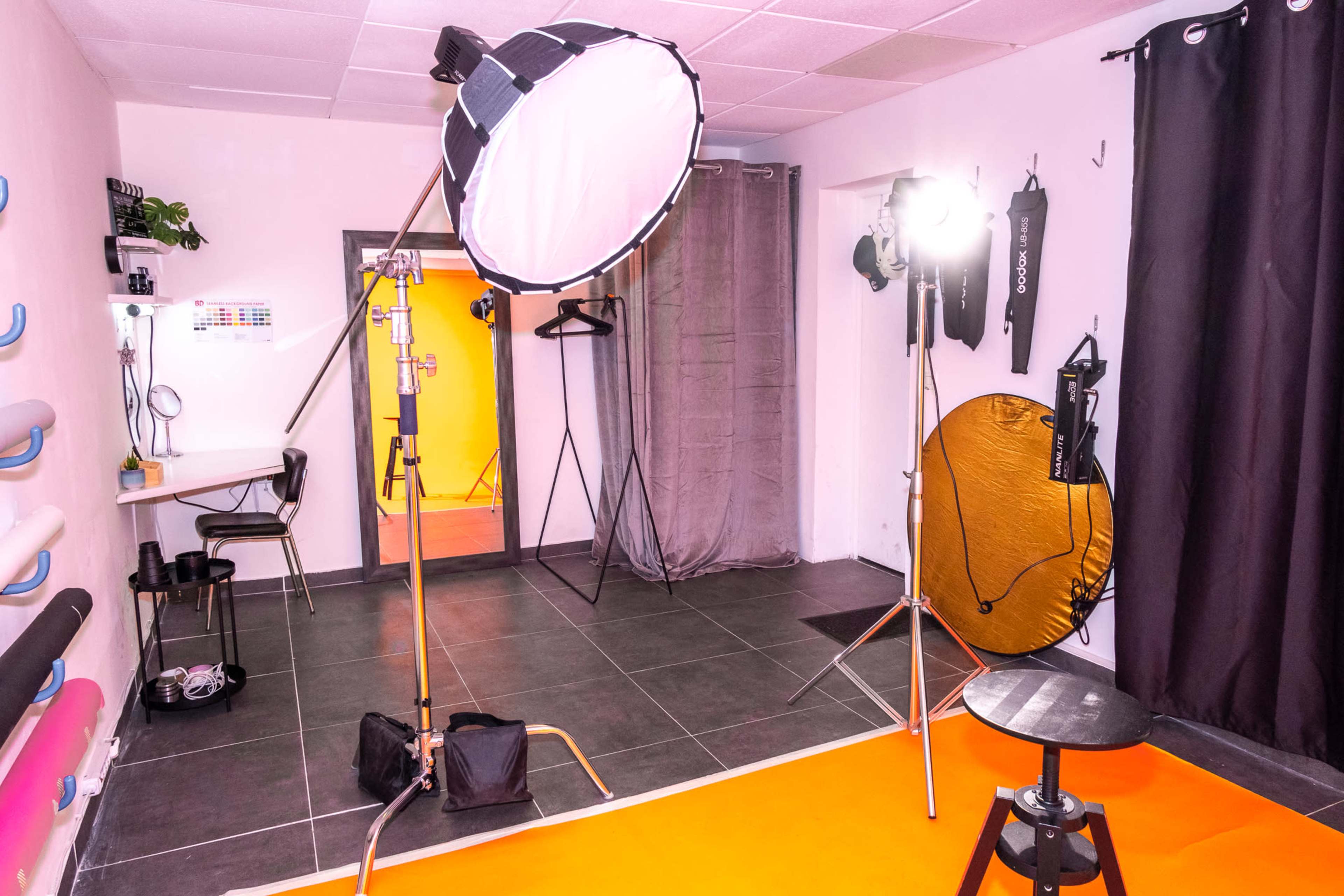 A photo studio with various lighting equipment, a backdrop, and props arranged in a well-defined space.