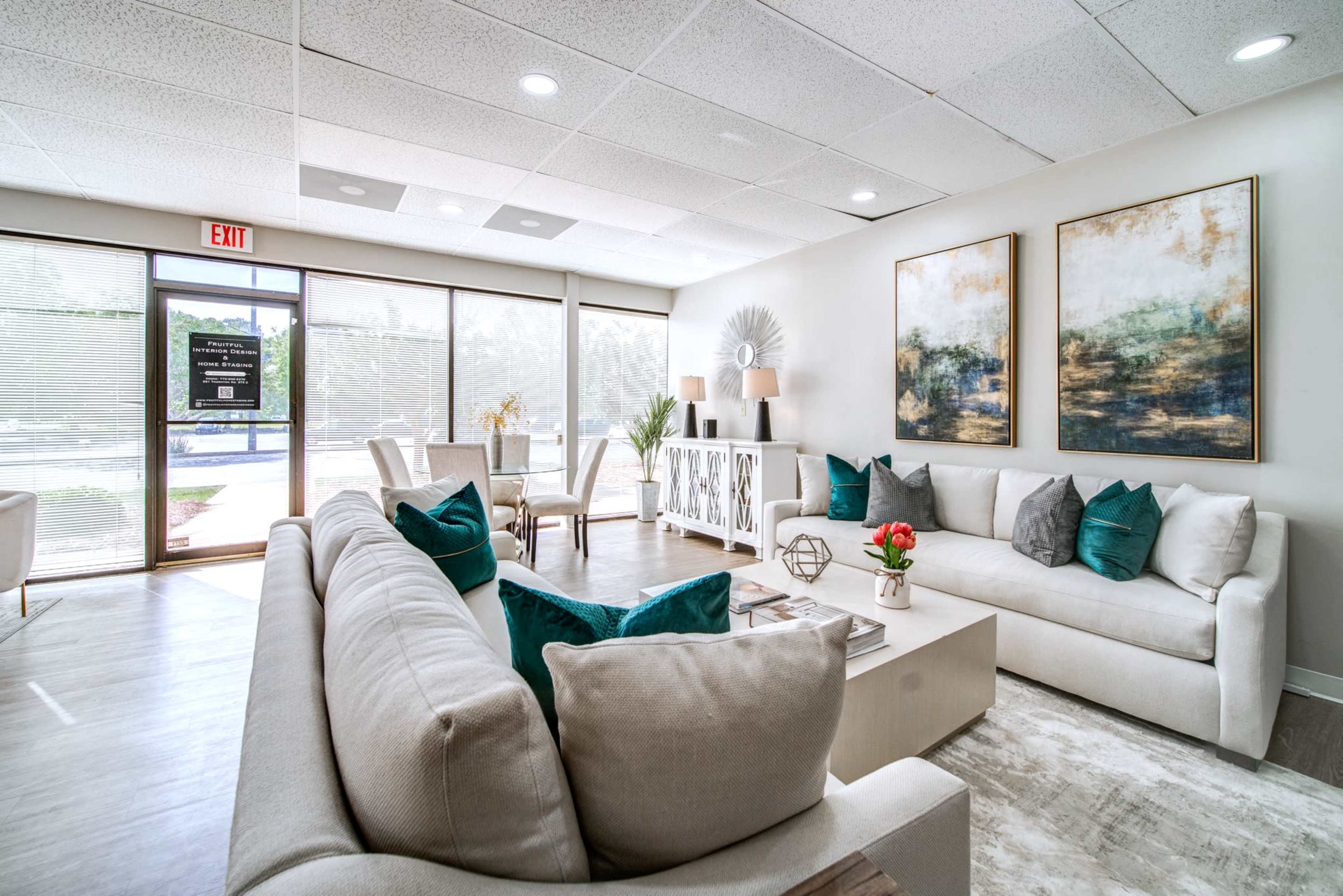 A modern waiting area with two sofas, decorative art on the walls, and floor-to-ceiling windows letting in natural light.