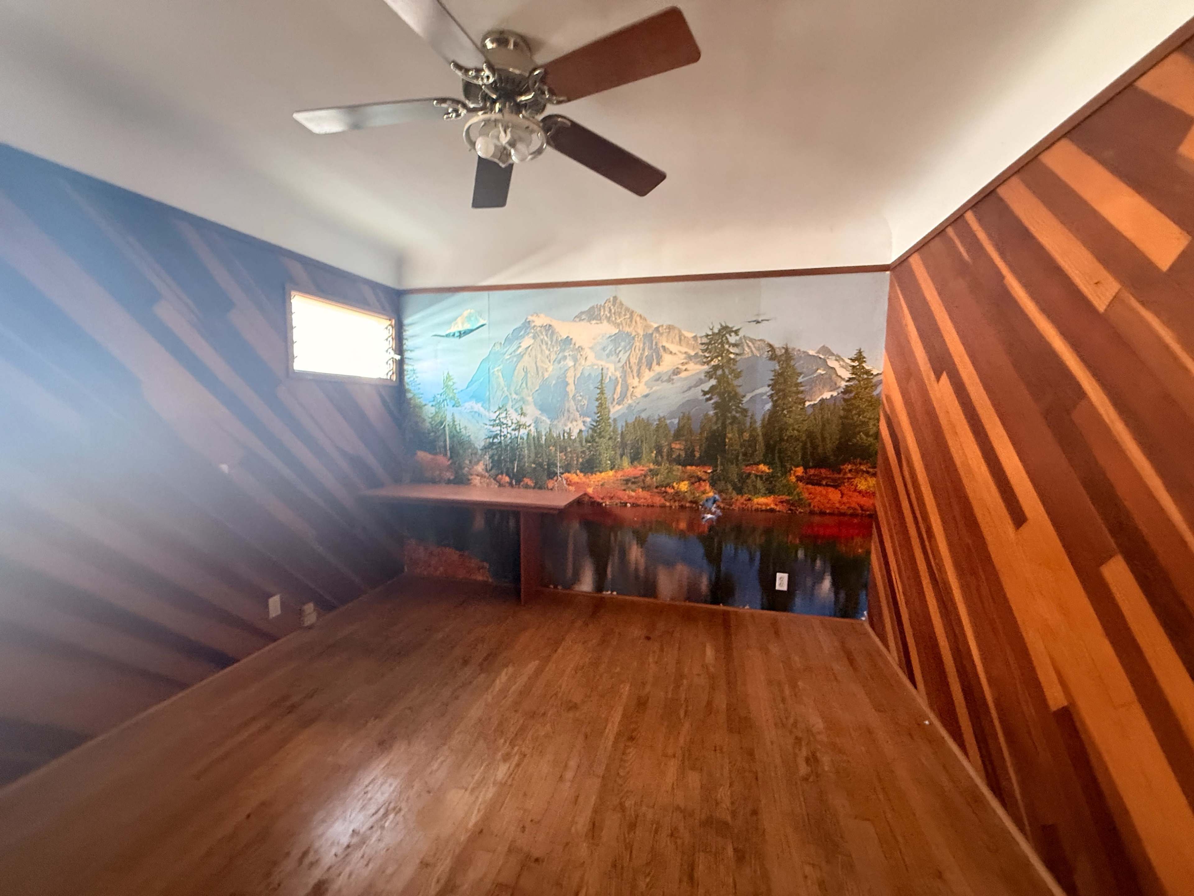 The room features a wooden wall design and a mural of a mountainous landscape with a lake and trees.