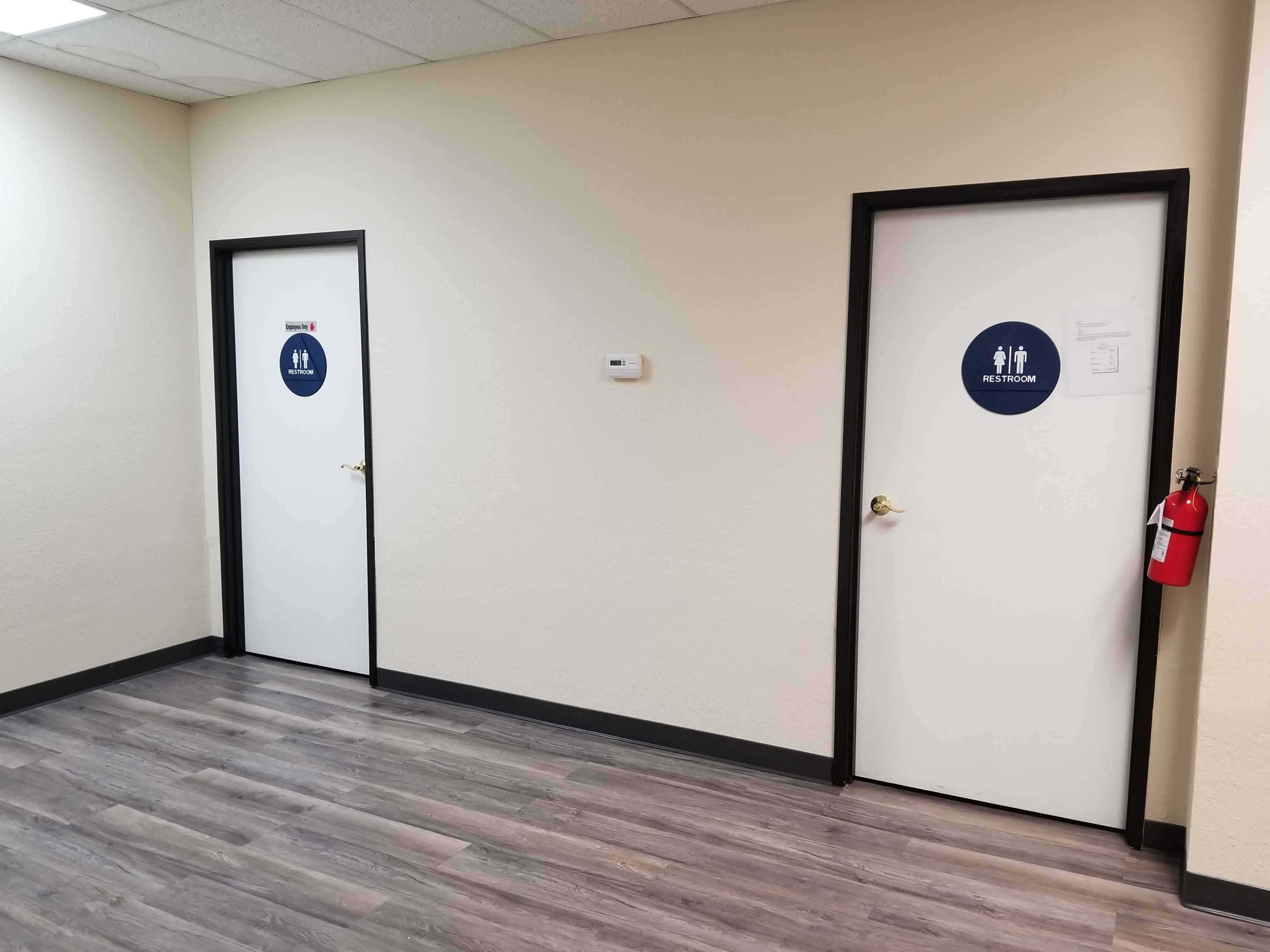 A corridor featuring two doors, one labeled "RESTROOM" and the other marked with a symbol indicating another type of restroom.