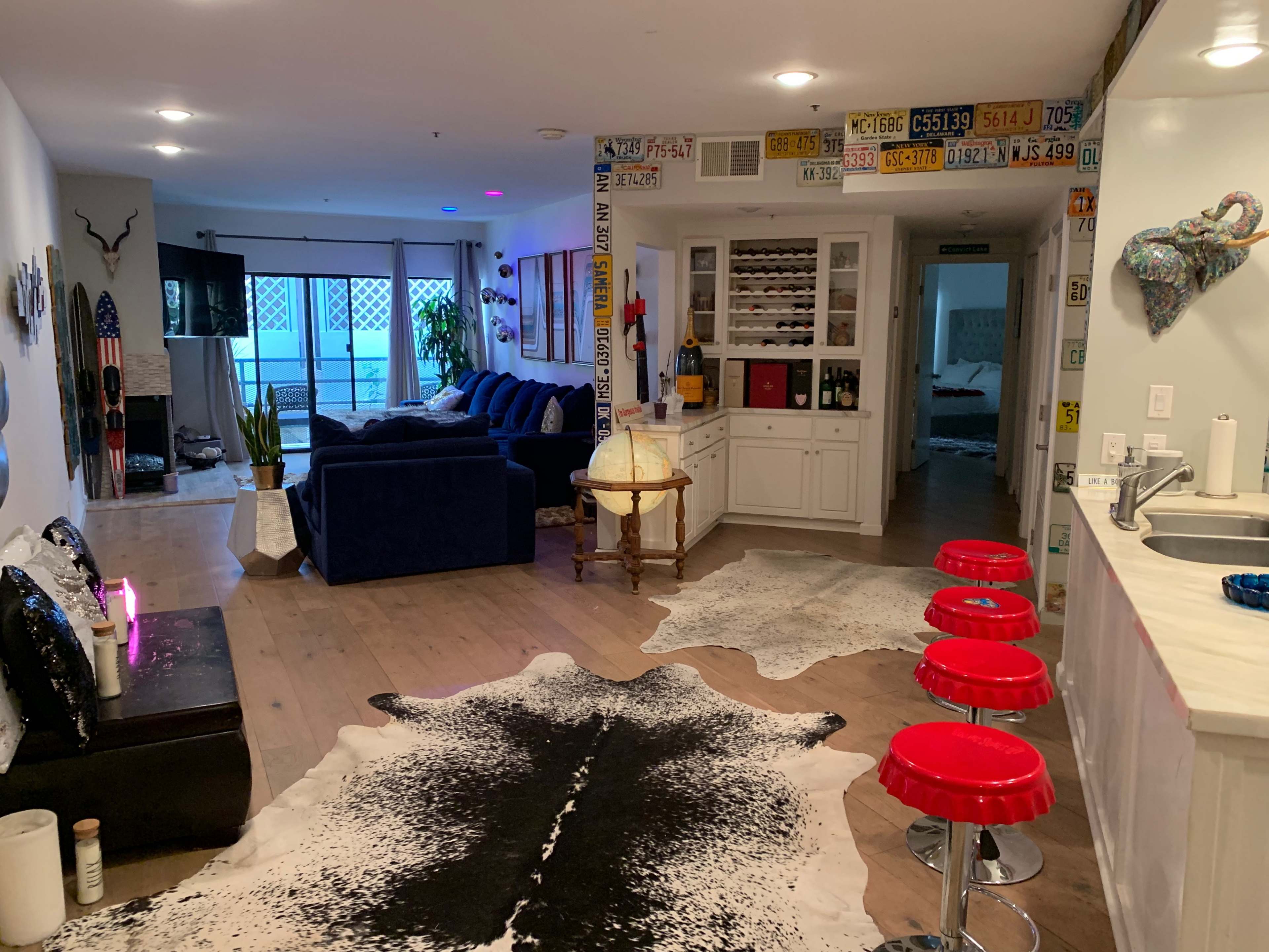 A modern living space with a blue couch, a dining table, and decorative elements including cowhide rugs and wall-mounted license plates.