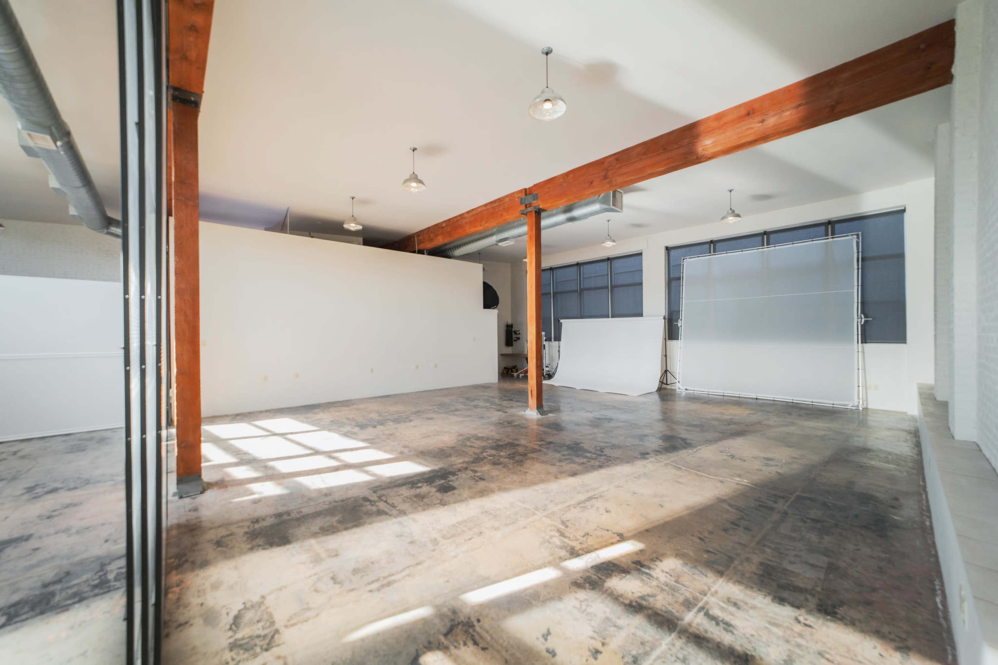 A spacious, industrial-style interior with polished concrete floors, large windows, and wooden beams.