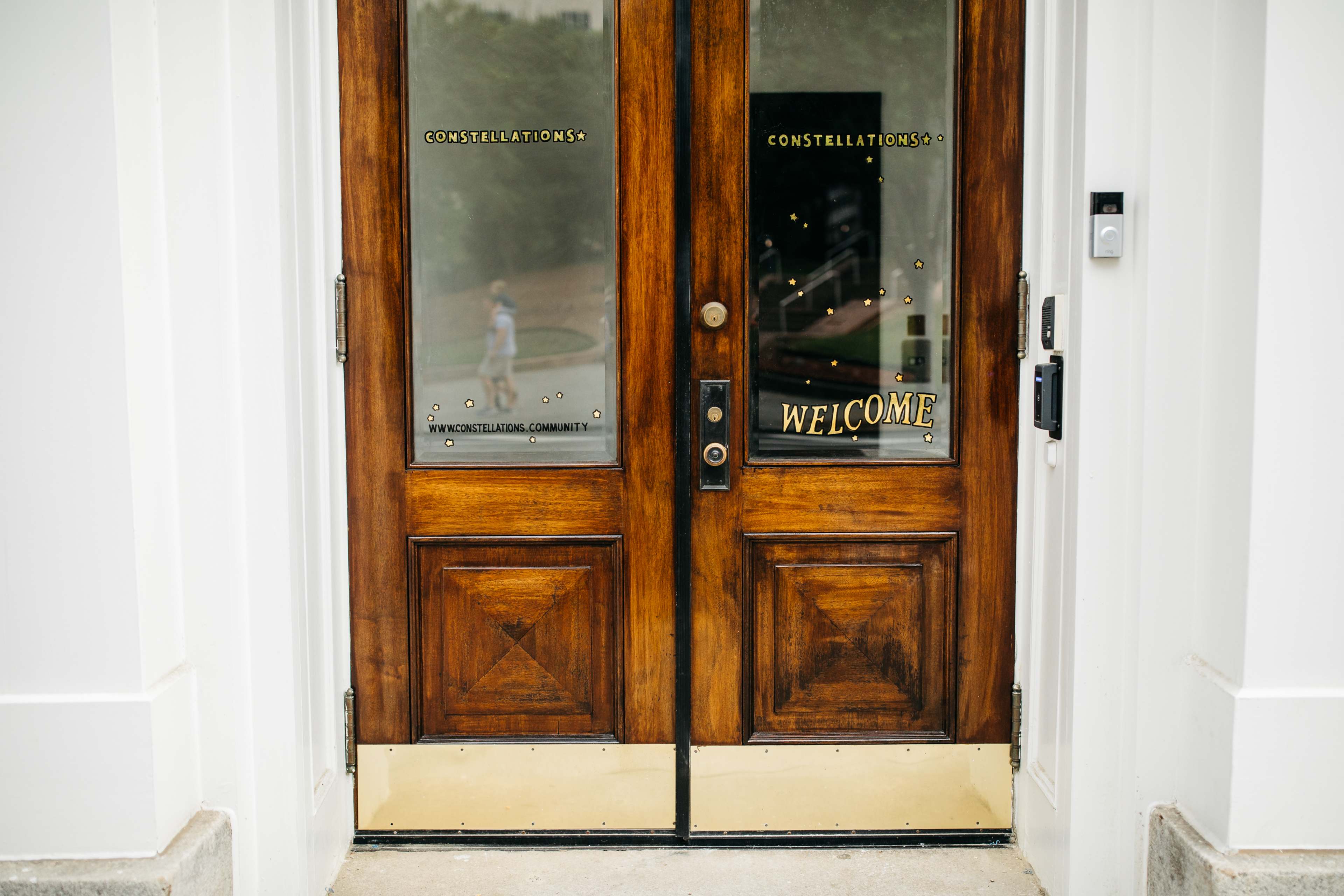 The image shows a pair of wooden doors with welcome signage and glass panels displaying the word "CONNECTIONS."
