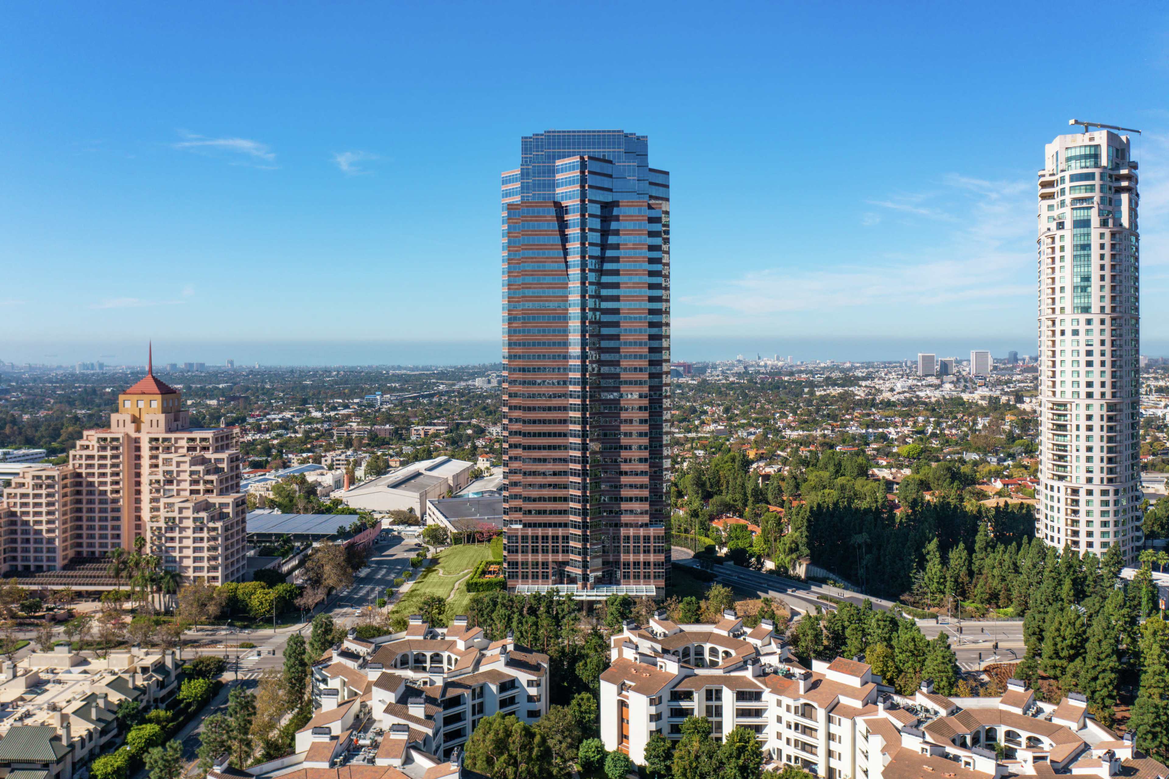 A collection of high-rise buildings and residential structures is set against a clear blue sky in an urban landscape.
