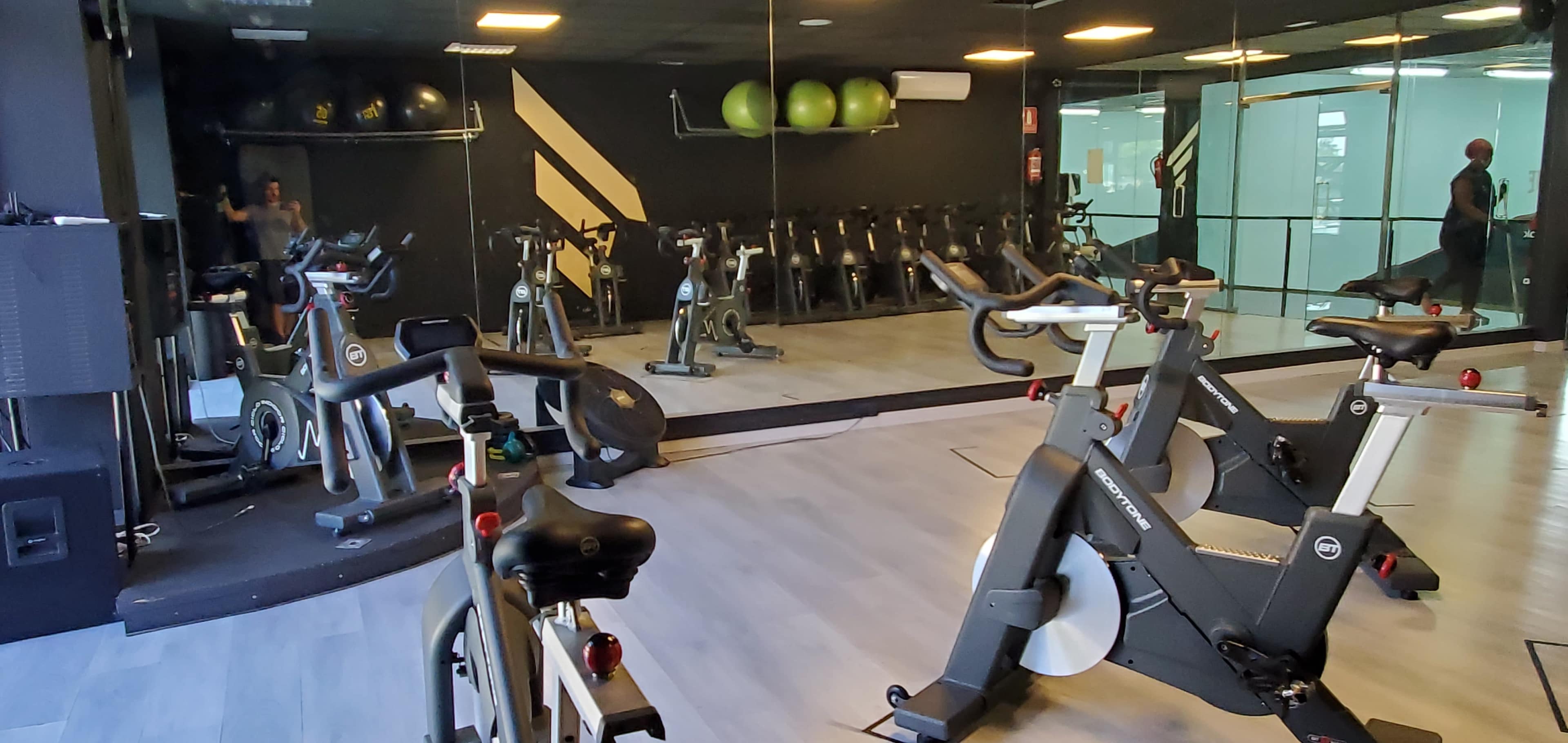 A modern gym interior with stationary bicycles and exercise equipment arranged neatly, reflecting a vibrant environment for fitness activities.