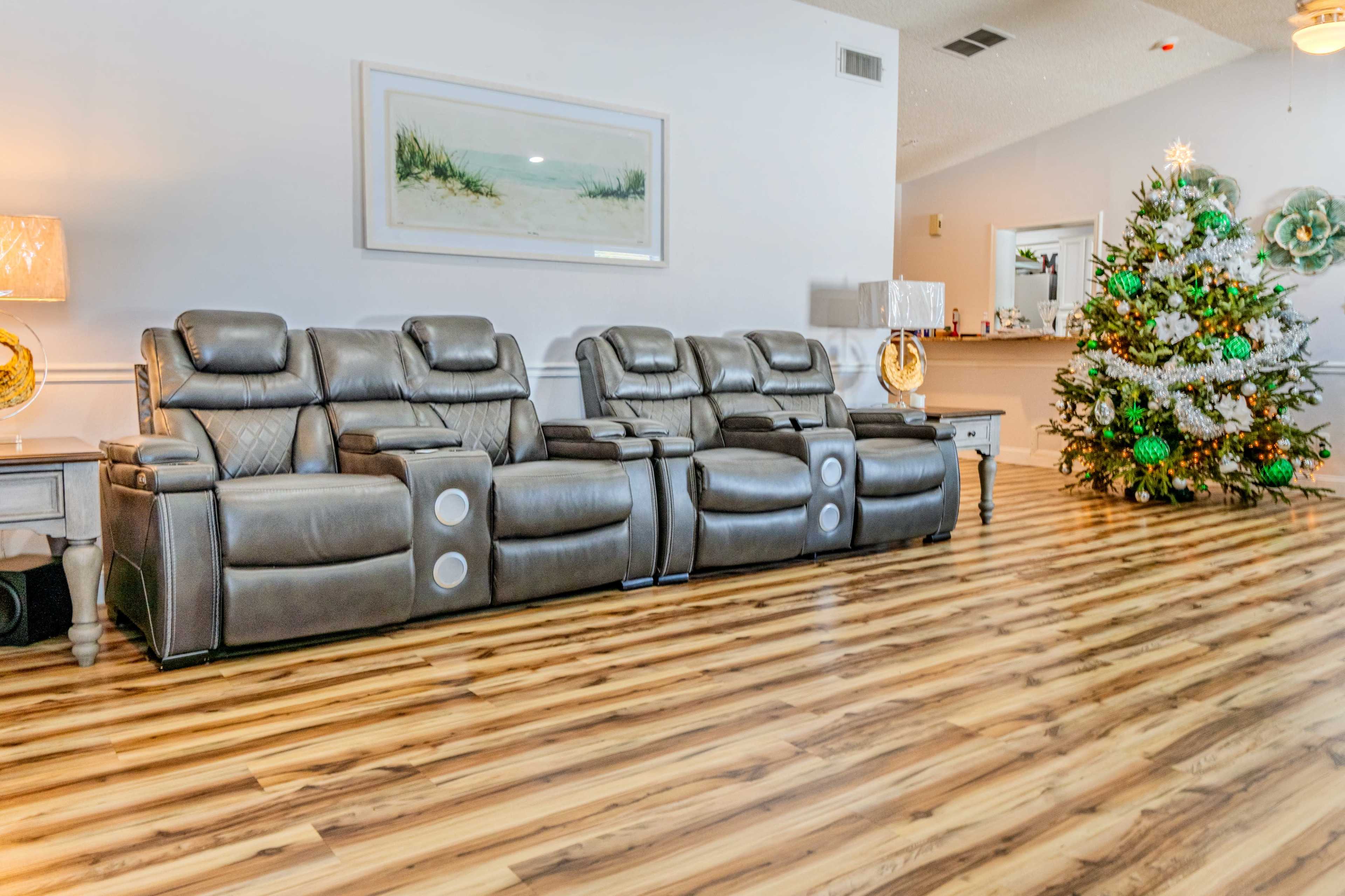 The image shows a living room with a set of gray reclining chairs and a decorated Christmas tree in the corner.