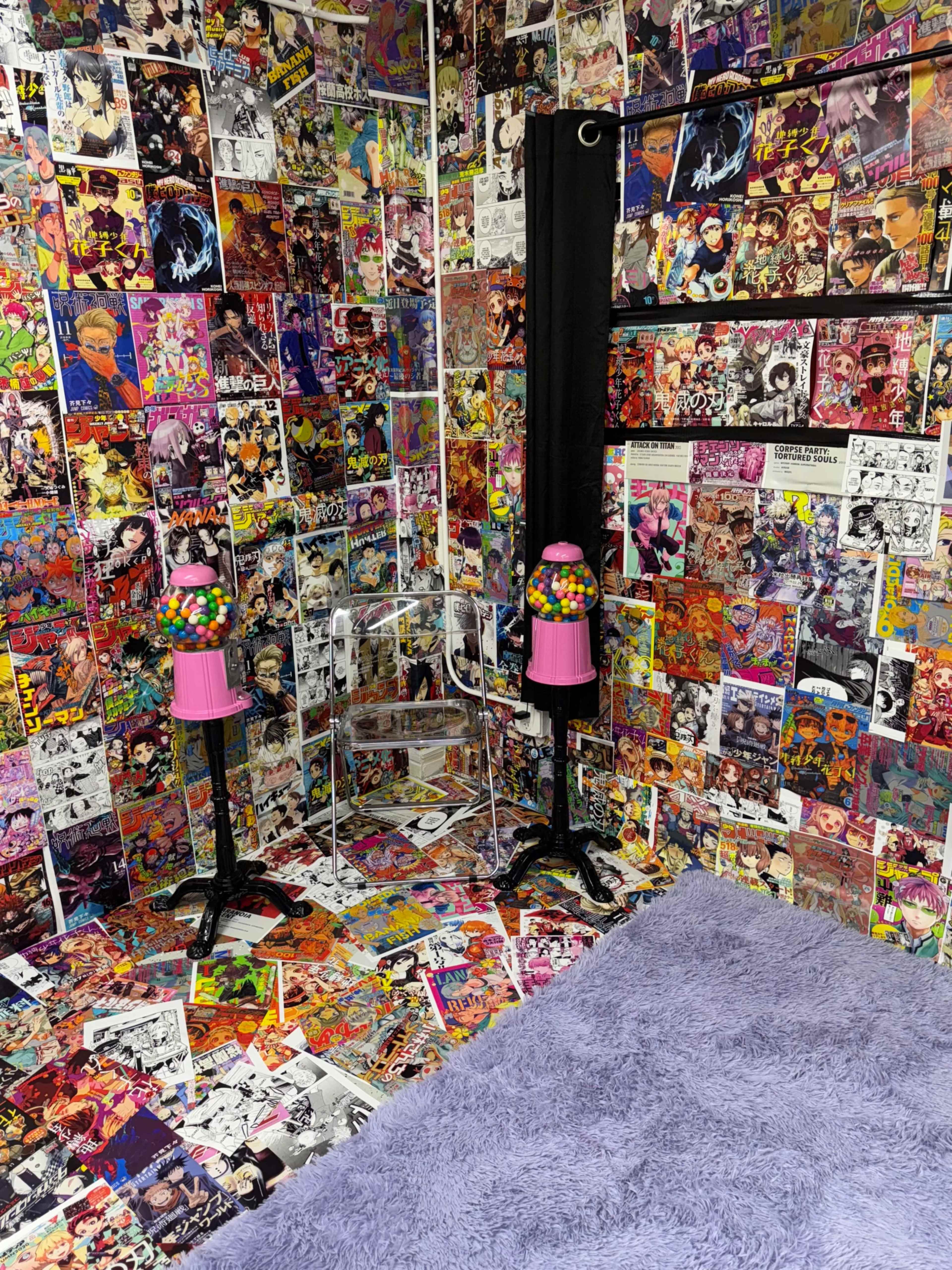 The image shows an eclectic room with walls and floors covered in vibrant, comic-style posters, featuring two pink gumball machines on stands.