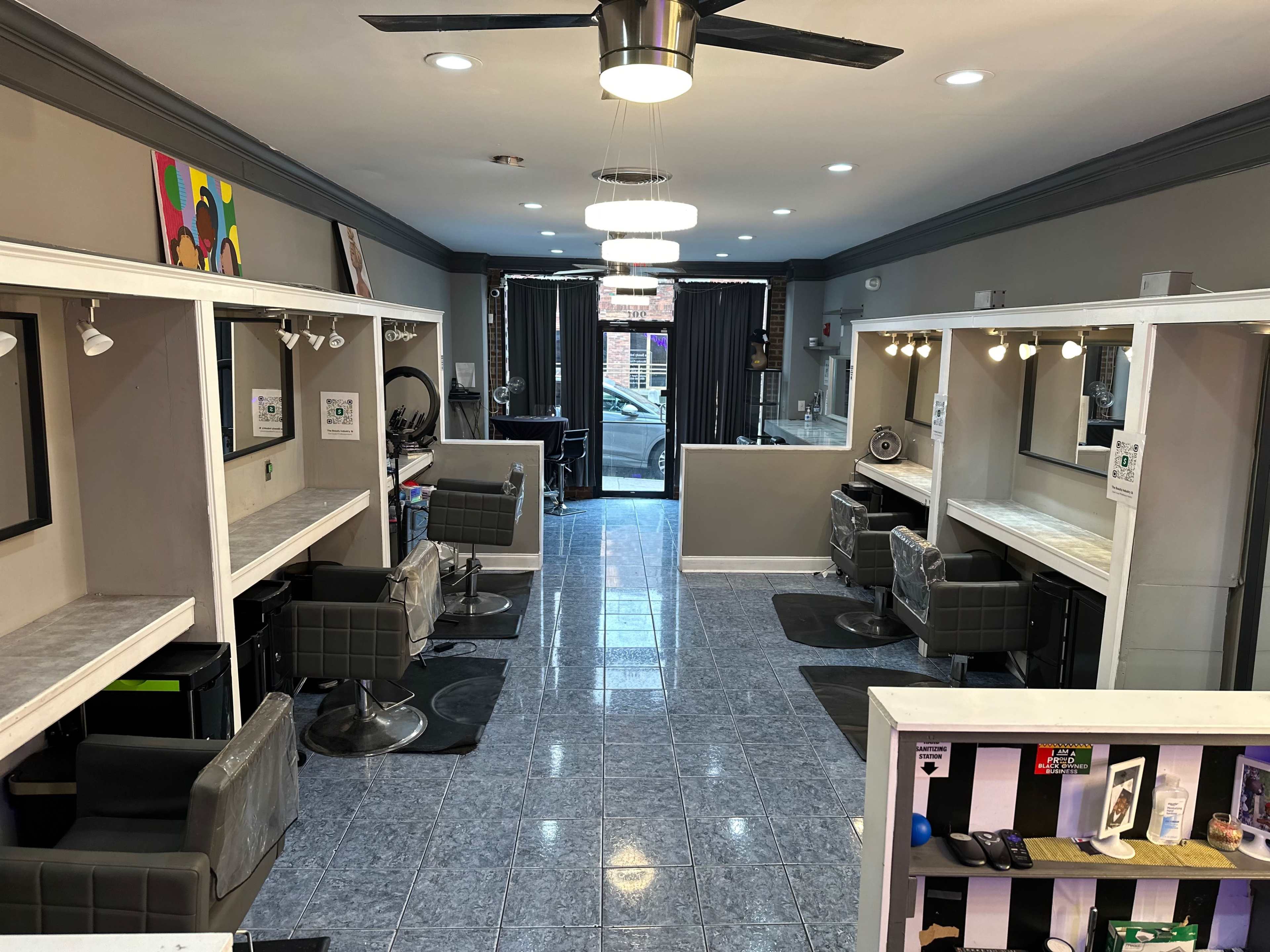 The interior of a hair salon featuring multiple styling stations with mirrors, chairs, and a spacious entrance area.