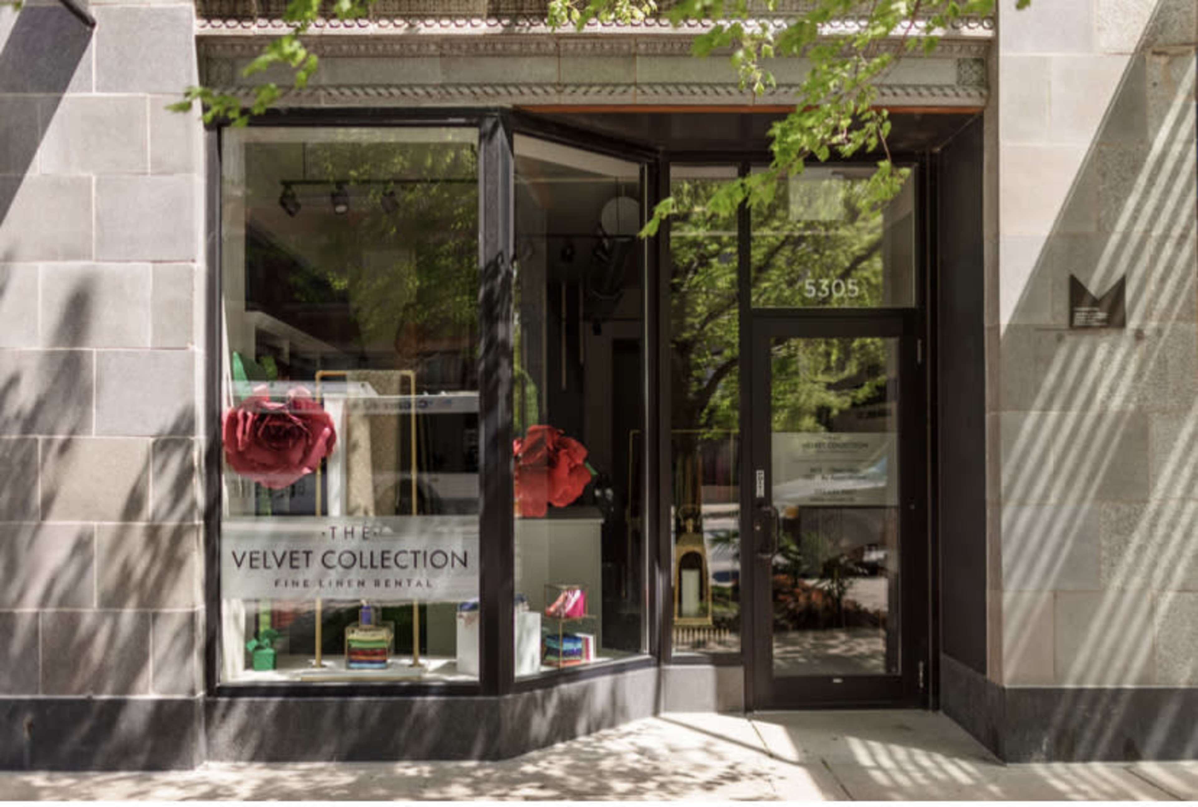 The entrance of a storefront named "The Velvet Collection" featuring large red rose decorations in the window.