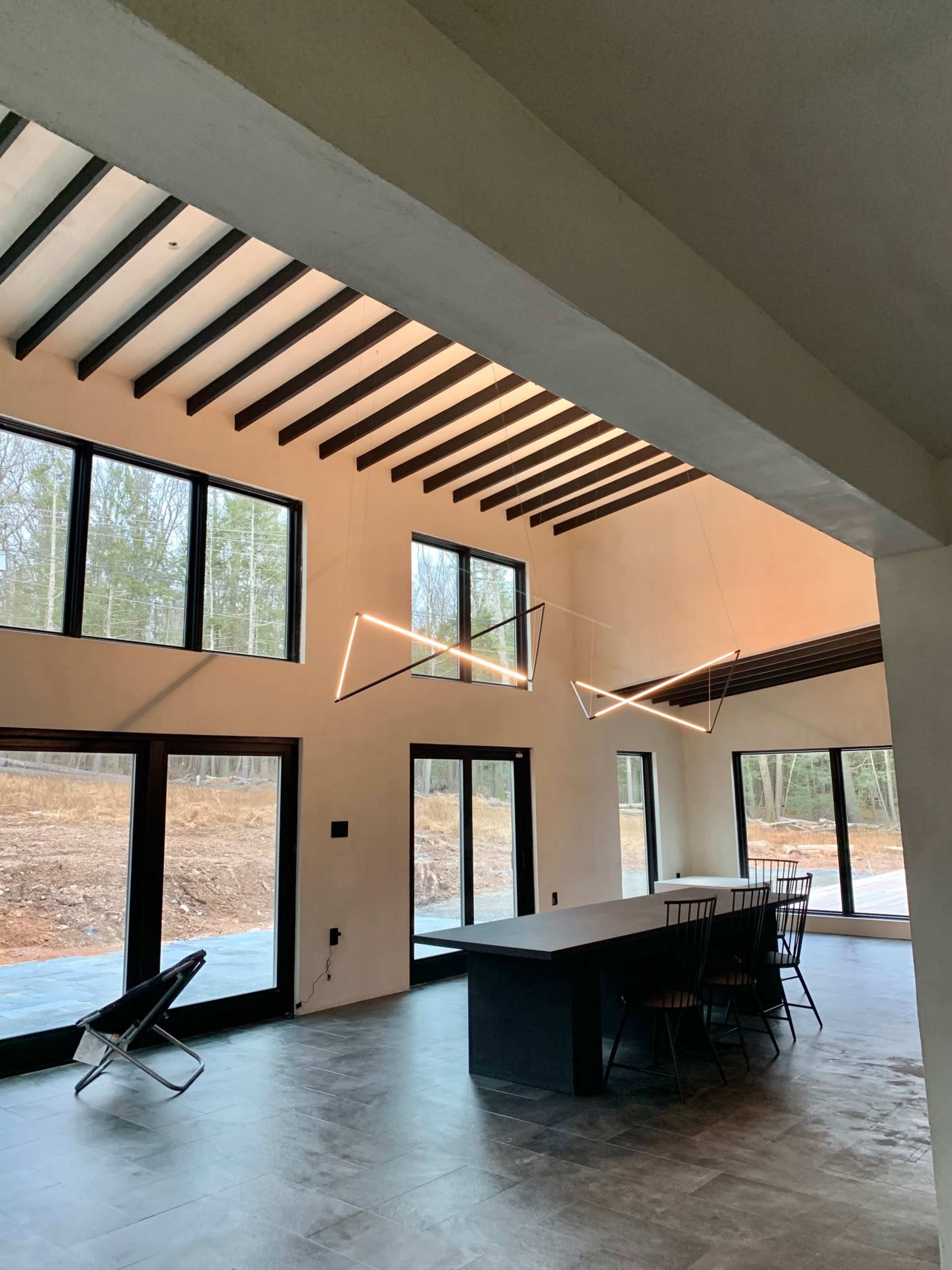 A modern dining area with large windows, a minimalist table, and geometric light fixtures.
